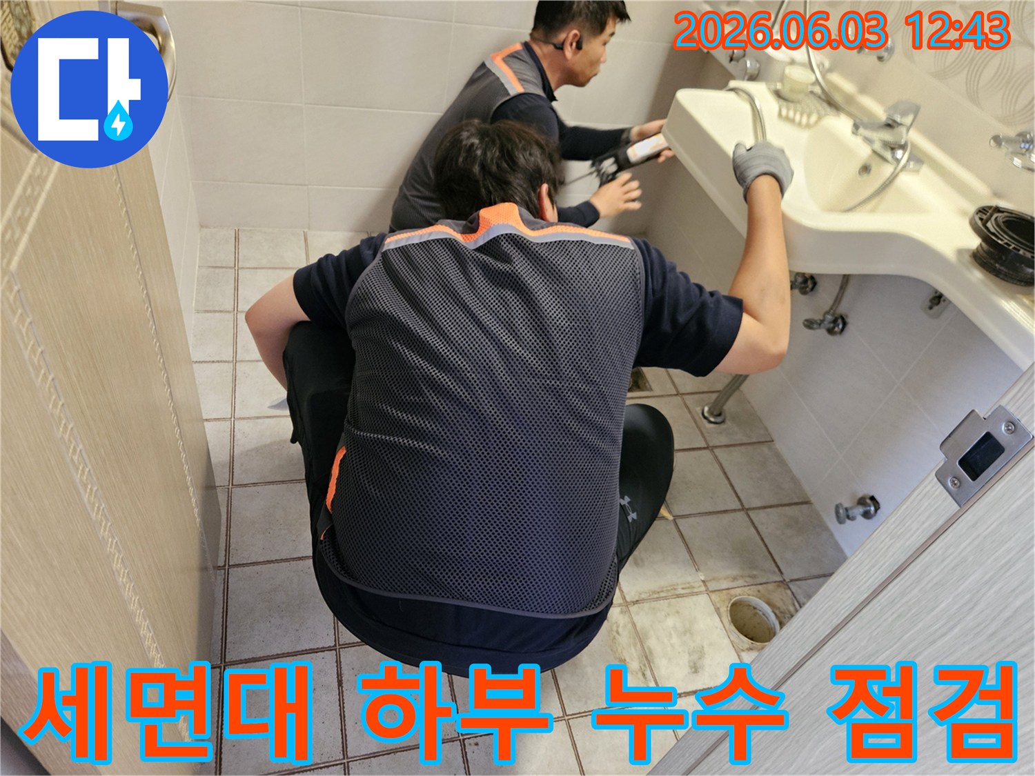 서울 중랑구 화장실에서-누수 전문가 두 명이-세면대 하부의 누수 여부를-정밀하게 점검하는 모습
