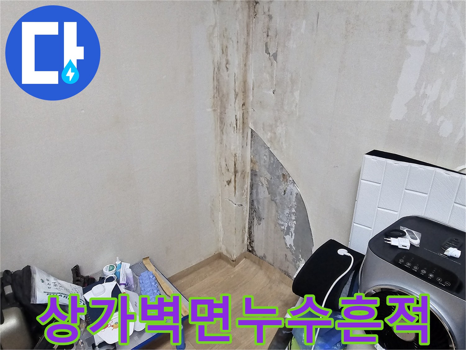 물에 젖어 변색된 상가 벽면과 일어난 마감재를 촬영한 사진입니다.