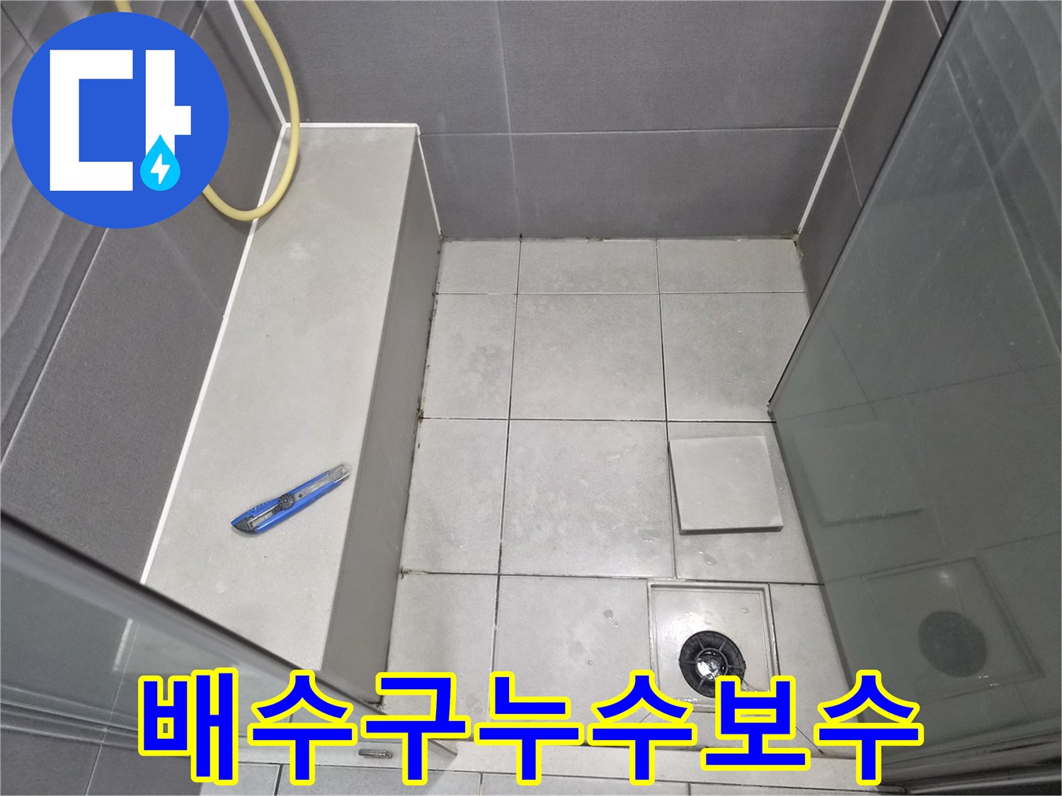 욕실-바닥-타일과-샤워-호스-그리고-누수-보수-작업을-위한-도구가-함께-담긴-사진입니다.