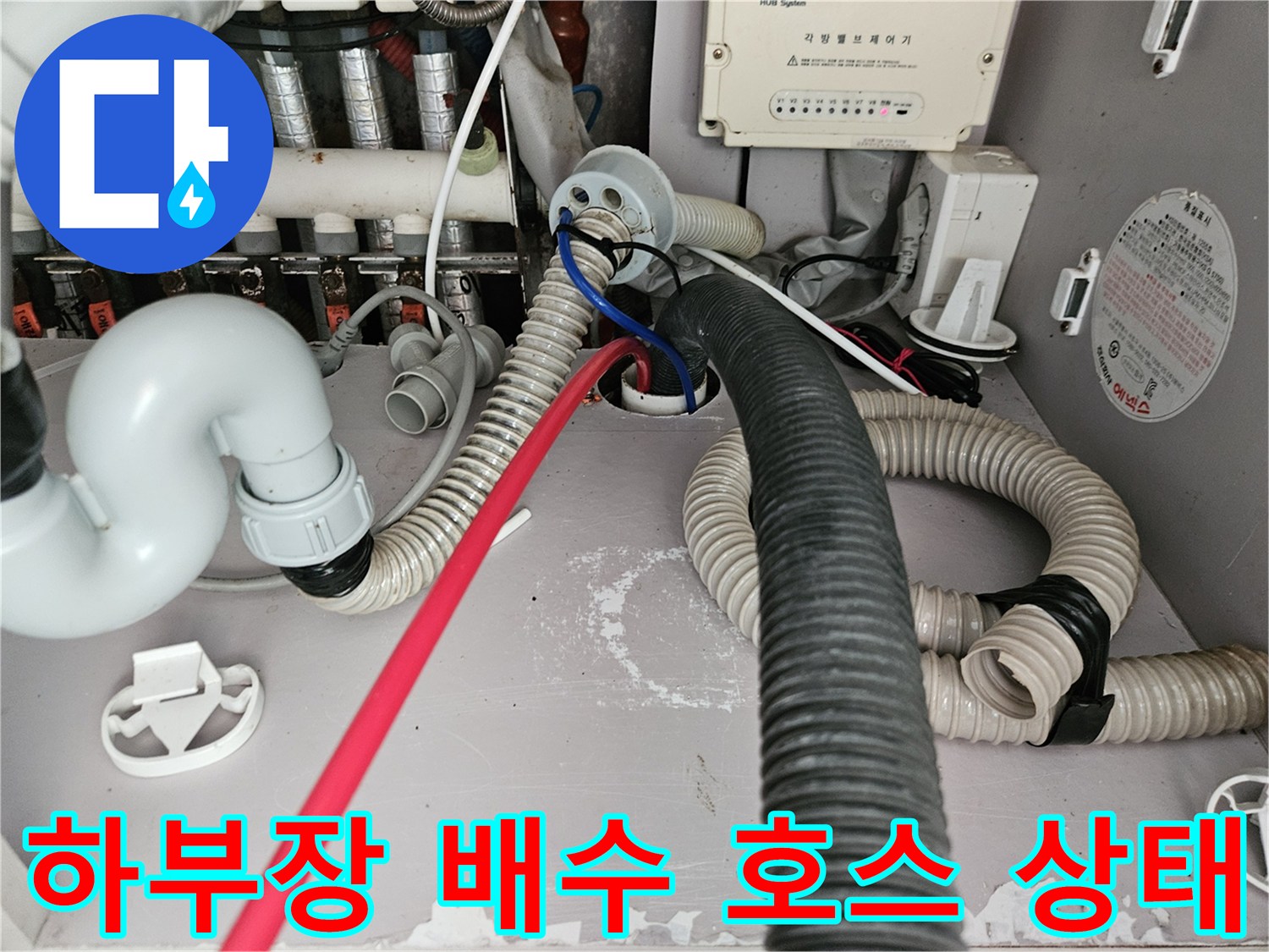 싱크대 하단에 설치된 다양한 규격의 배수 및 급수 호스 사진입니다.