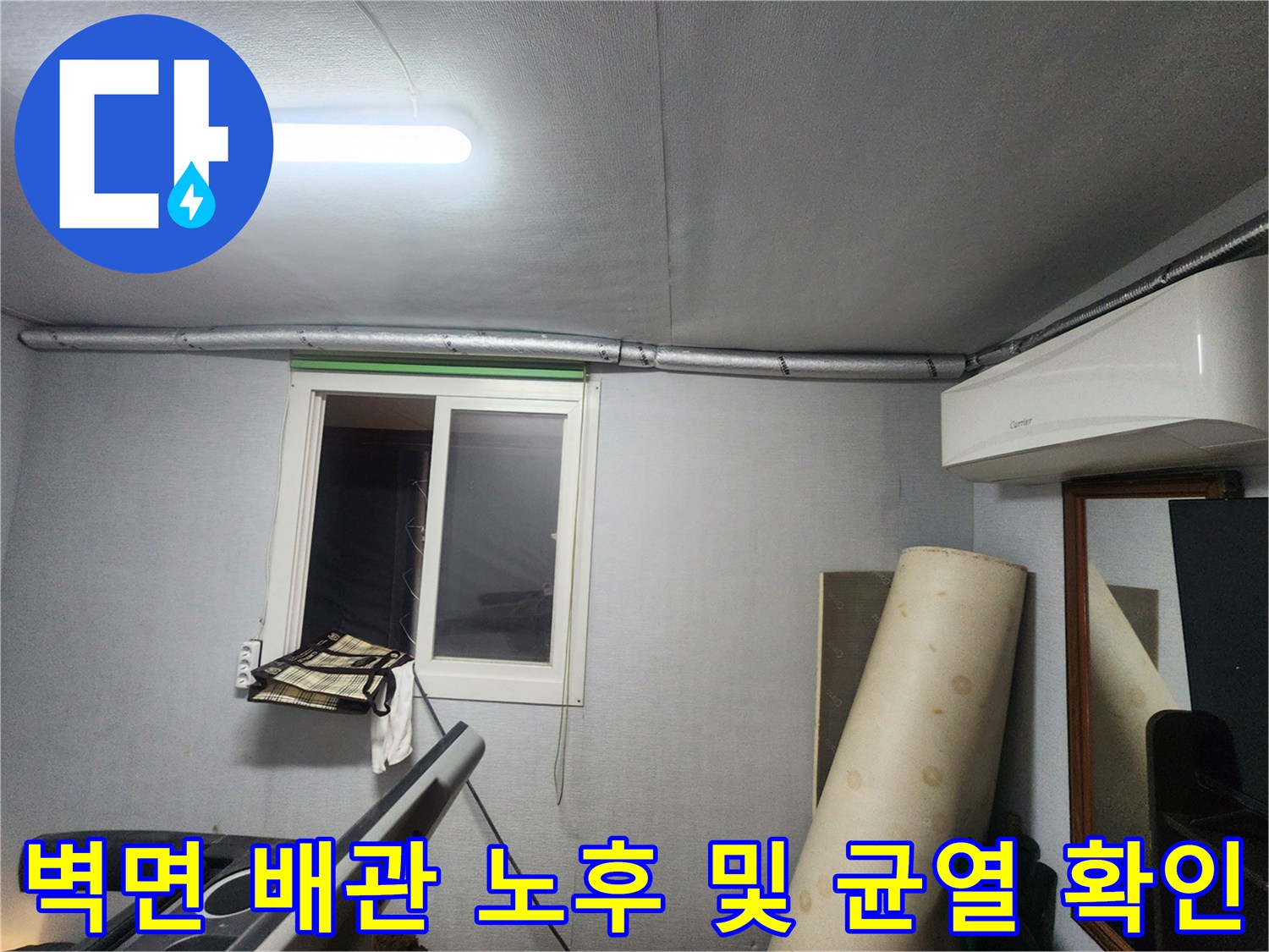 창문 옆 벽면에 설치된 수도 배관의 상태를 정밀하게 점검하는 모습