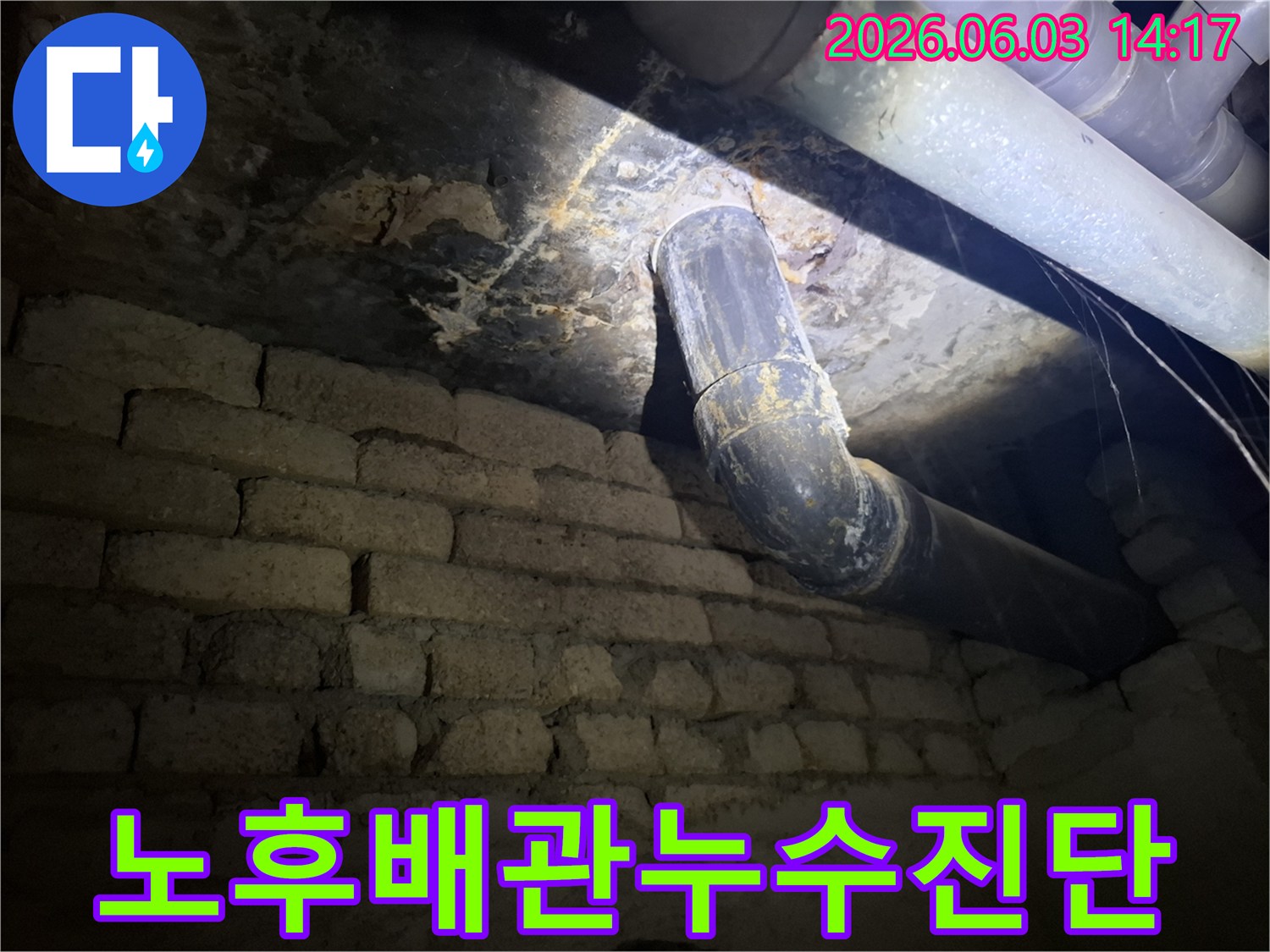 어두운 지하 공간의-낡은 벽돌 벽과-오래된 배관 주변에서-발견된 누수 흔적을-조명으로 비추어-정밀하게 진단하는 모습