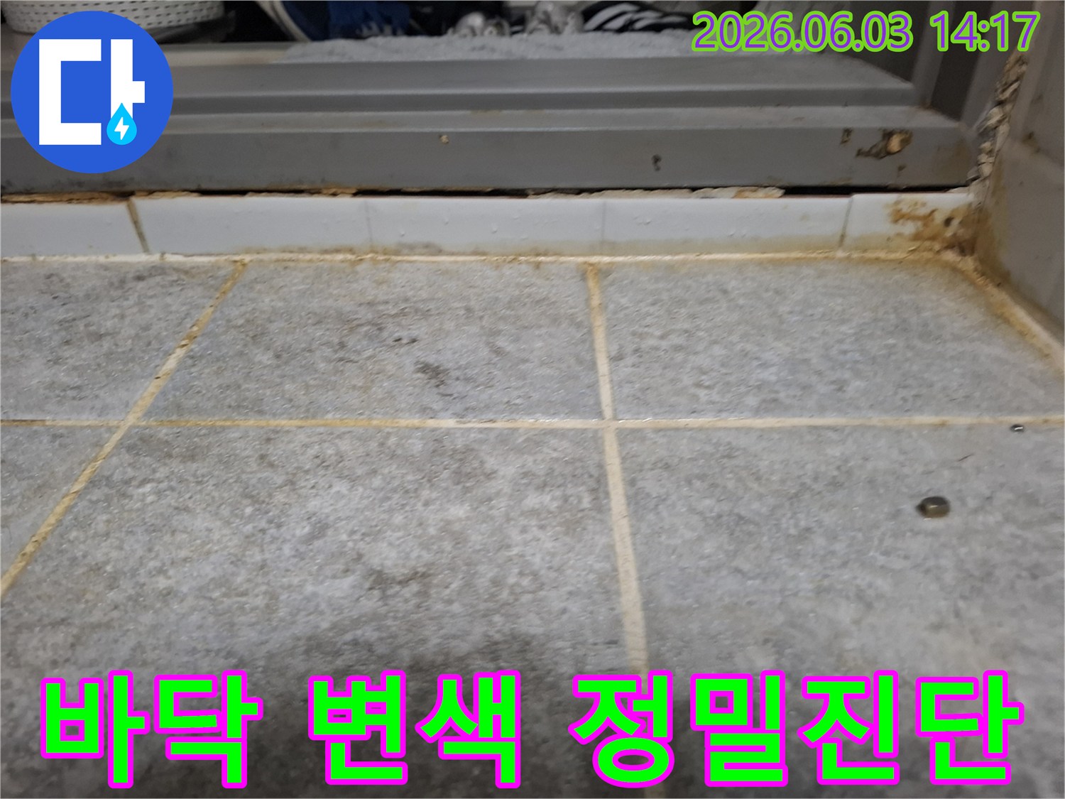 욕실 바닥 타일과 문턱 경계면에서 발견된-오랜 누수로 인한 심각한 변색과 오염의 증거입니다.