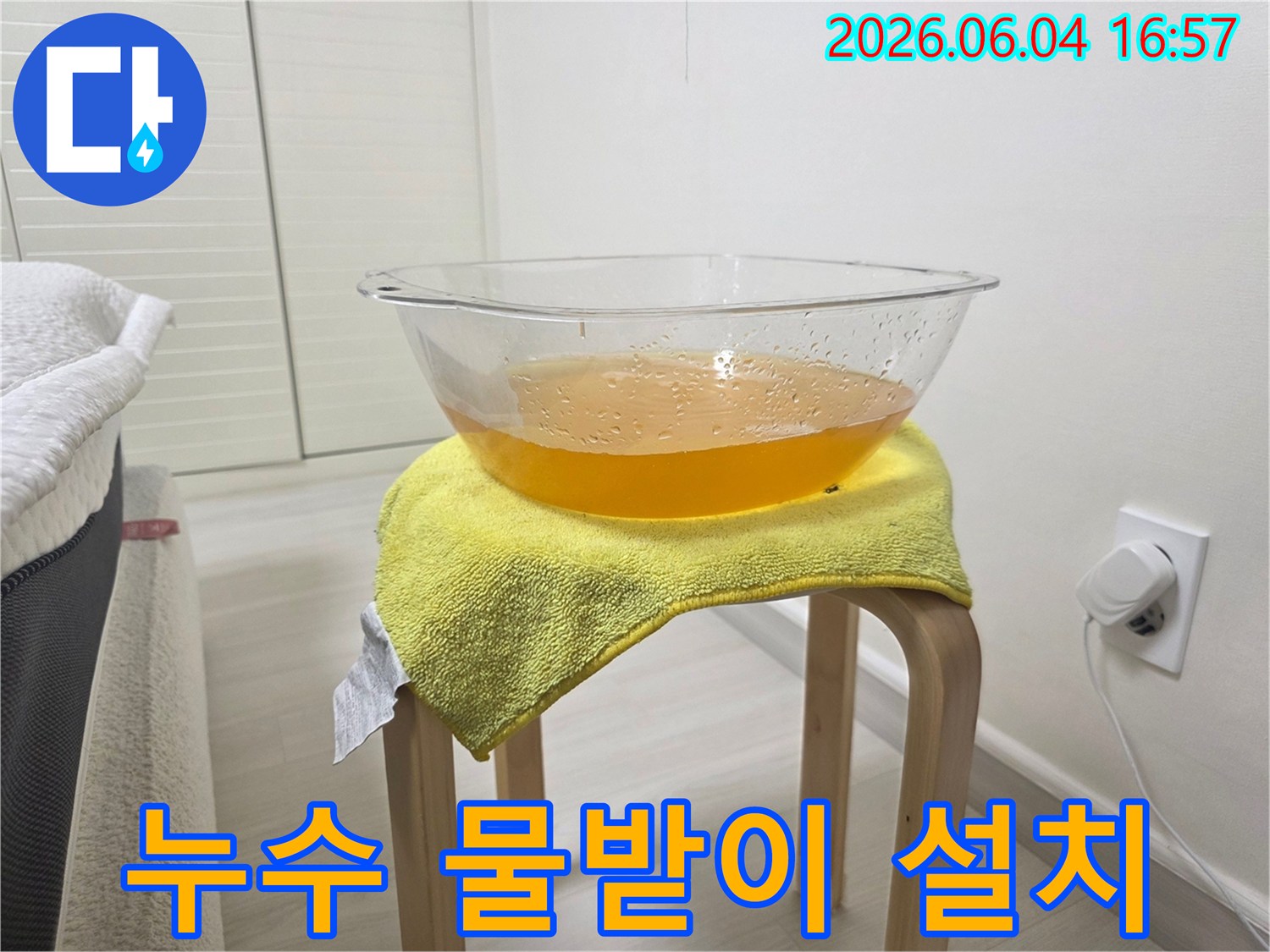 천장에서 물이 떨어지는 긴급 상황에서-바닥 손상을 막기 위해-설치된 임시 물받이와-노란 수건의 모습