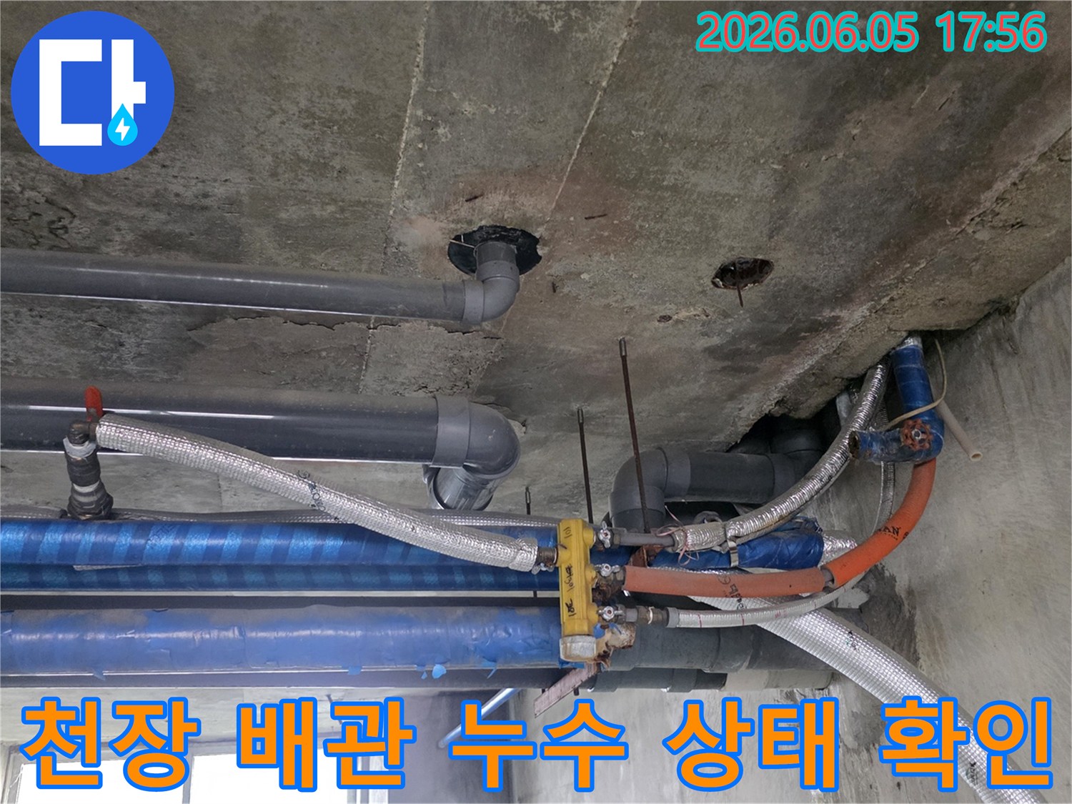 다양한-배관들이-복잡하게-얽혀-있는-콘크리트-천장-아래-누수-탐지-전문가가-현장을-점검하는-모습