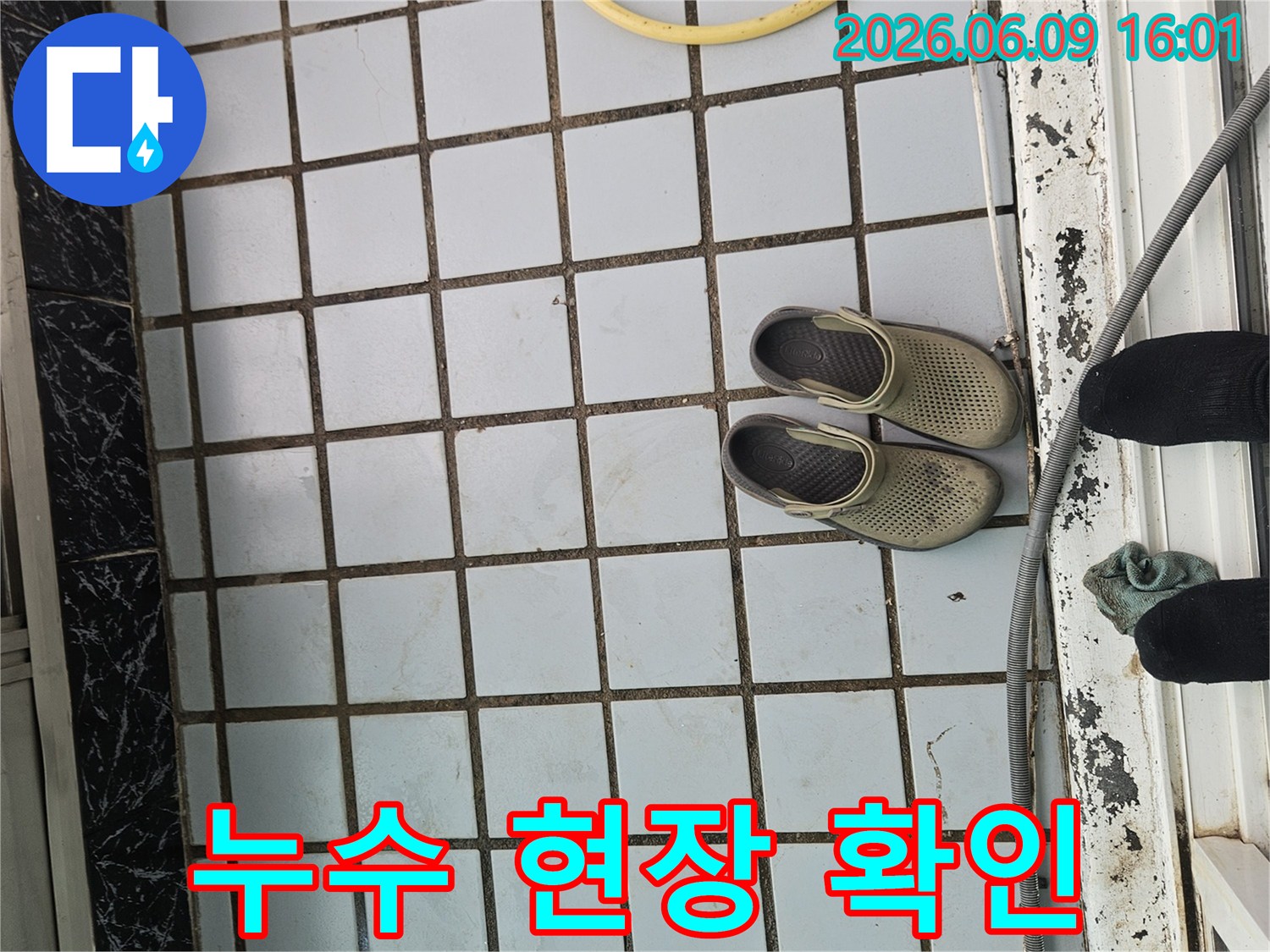 누수-전문가가-오염된-타일-바닥과-작업-준비물을-통해-누수-현장을-점검하는-사진입니다.