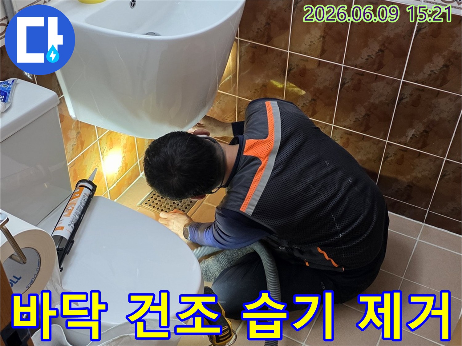동두천 아파트 욕실에서 전문 기술자가 누수 보수 후 바닥의 습기를 제거하고 건조 작업을 진행하는 모습