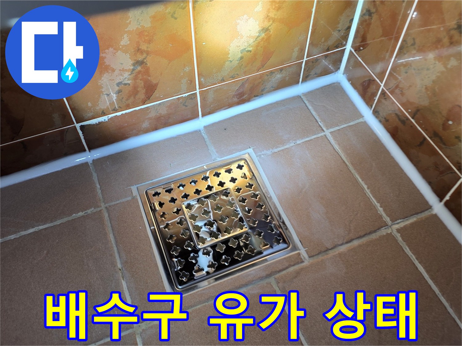 화장실 배수구 덮개와 주변 타일의 정렬 및 마감 상태를 보여줍니다.