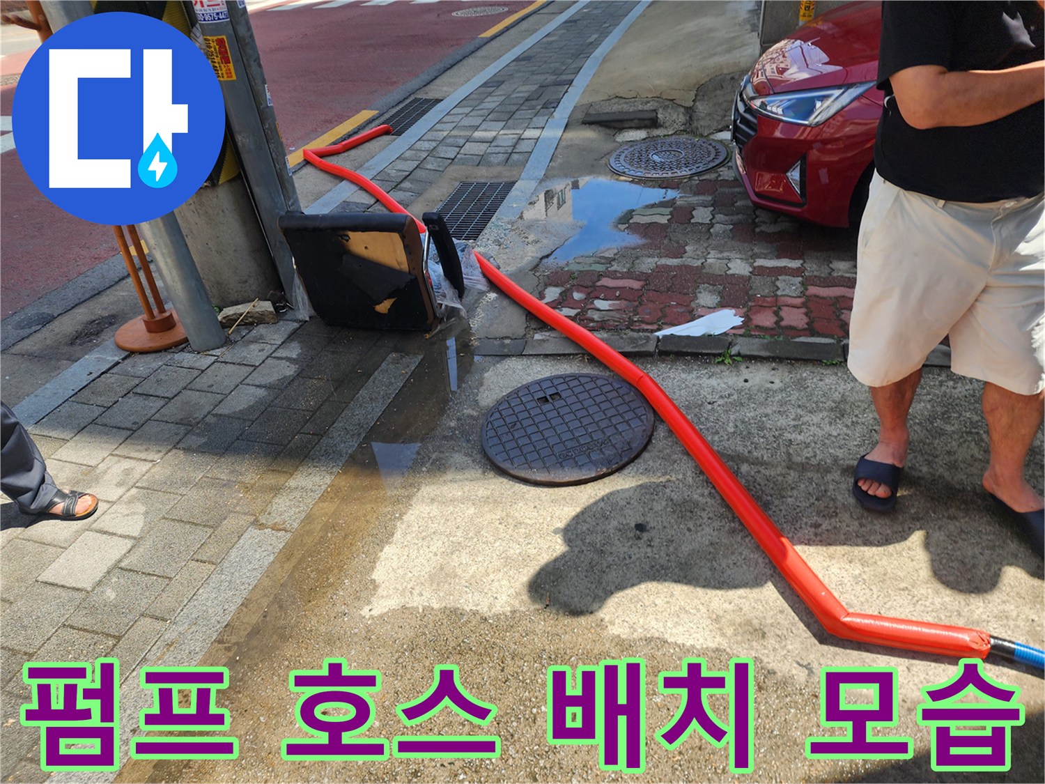 맨홀 주변 작업-역류한 물을 빼내기 위해 펌프 호스를 설치했습니다.