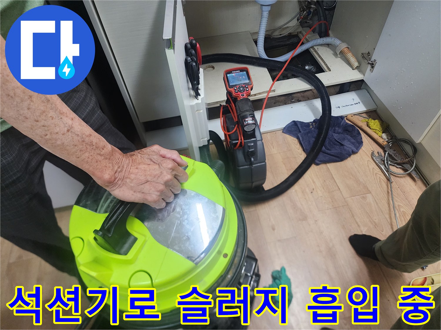 싱크대 하부장 내부에서-강력한 석션 장비를 이용해 배관 속 이물질을 빨아들이는 모습