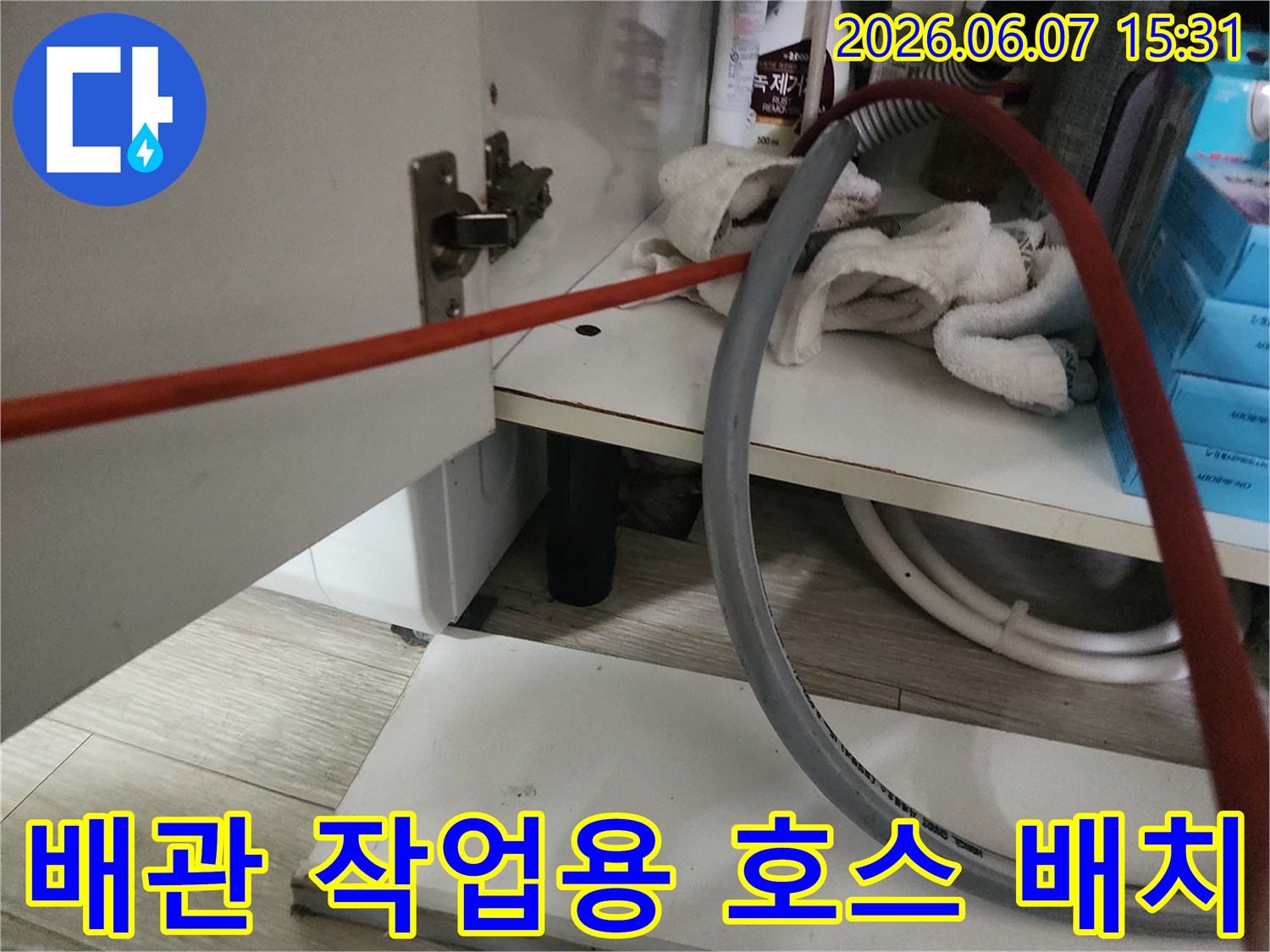 싱크대 하부장 내부의 배관 장비와 정리된 물품들