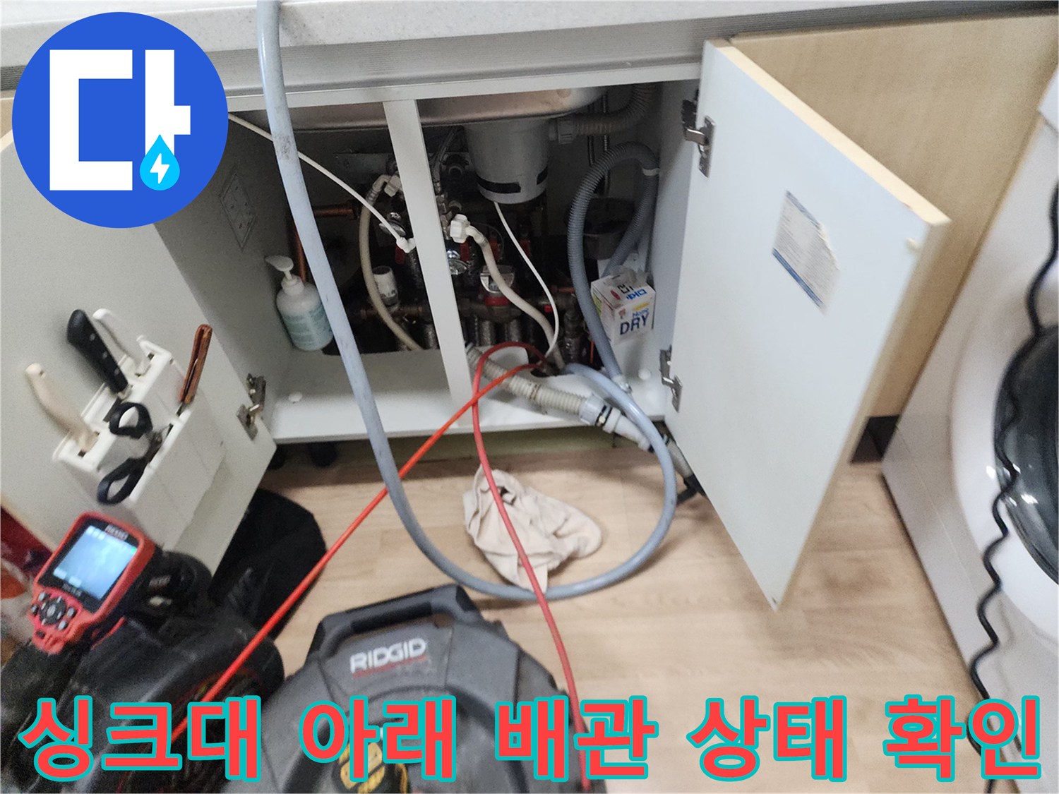 싱크대 하부장 내부의 복잡한 배관과 스케일링 장비 모습