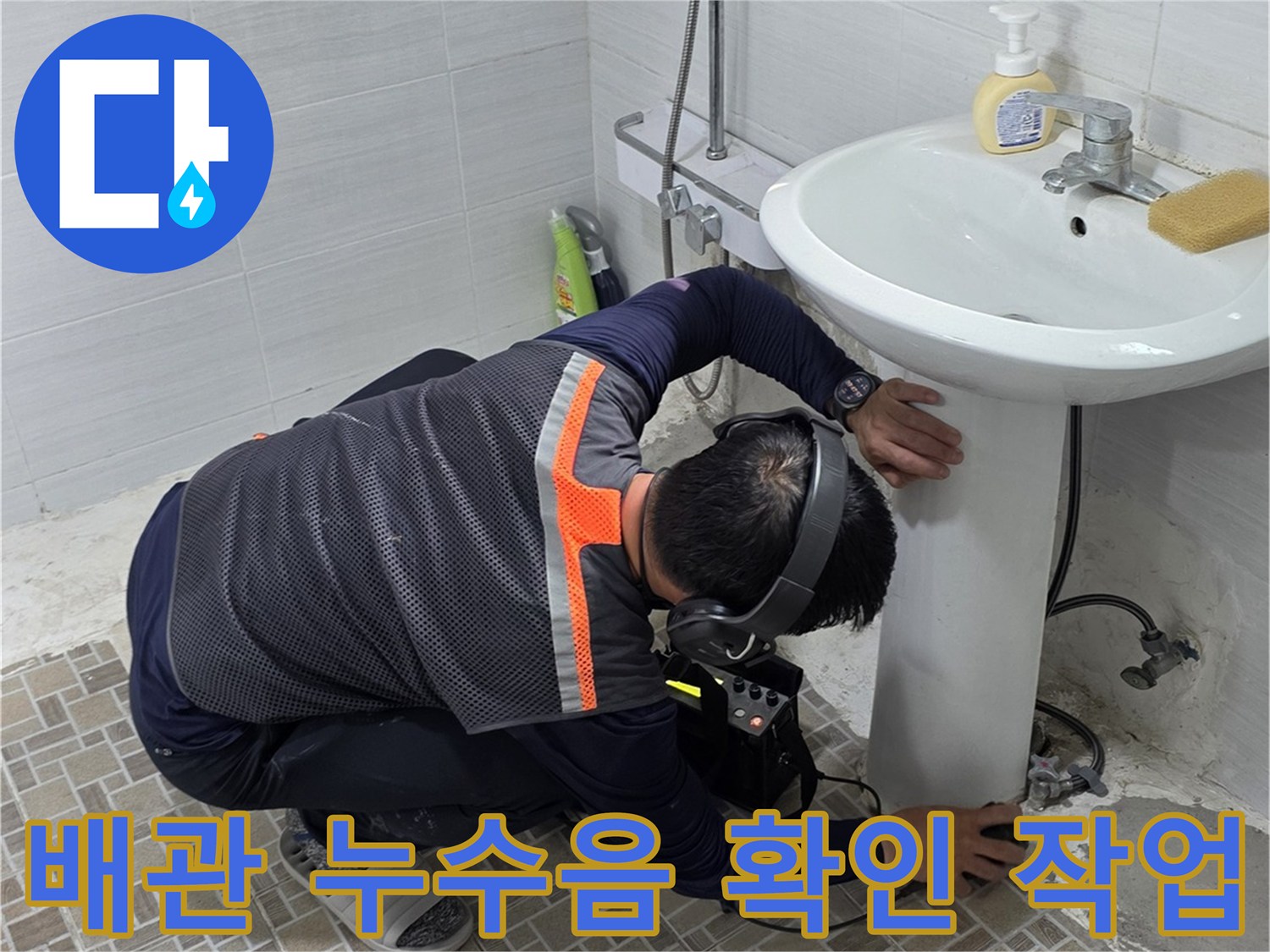 세면대 아래 배관 부위에서 소음을 추적하며 점검하는 엔지니어의 모습