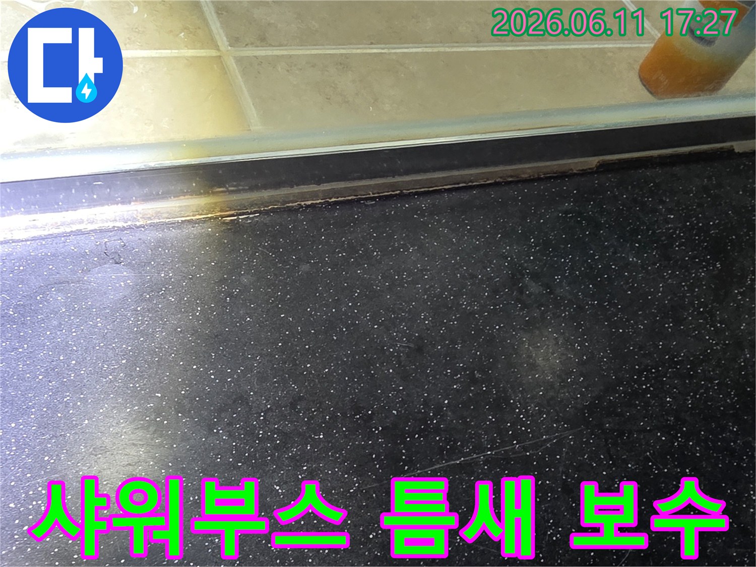욕실 샤워부스 하단-타일 틈새에서 발생한 누수 흔적과 보수 필요성을 보여주는 사진