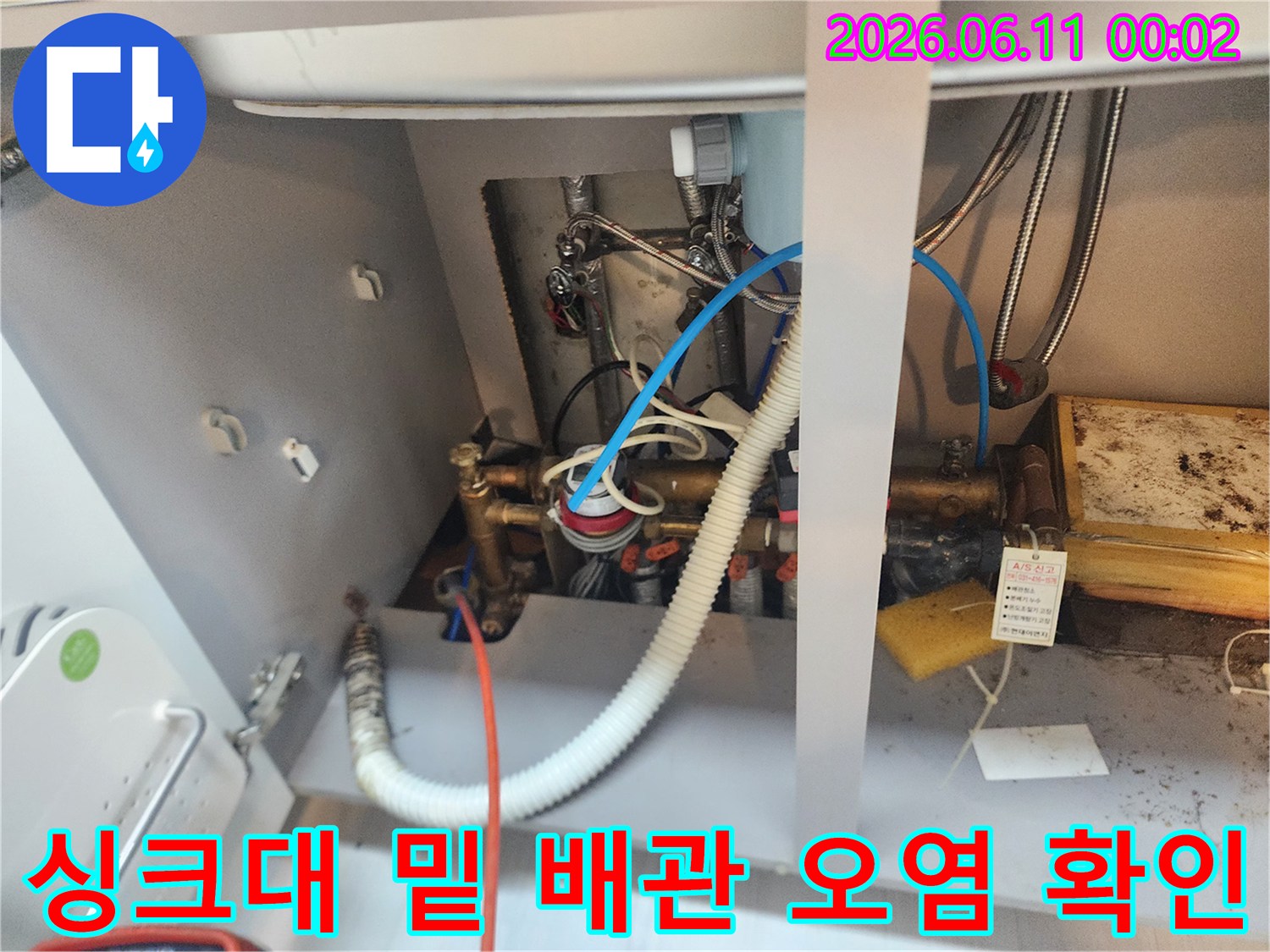 싱크대 하부장 내부의 밸브와 배수 호스 연결 부위 모습입니다.