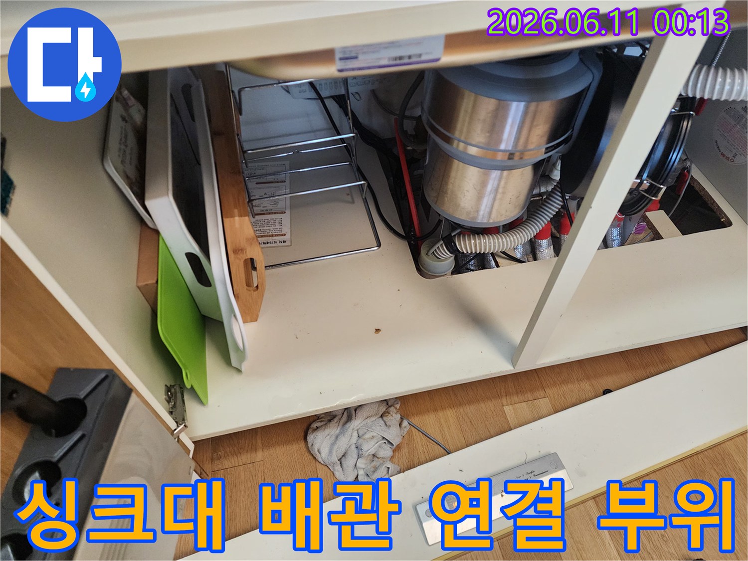 싱크대 하부장 내부의 금속 배관과 배수 호스 연결 모습