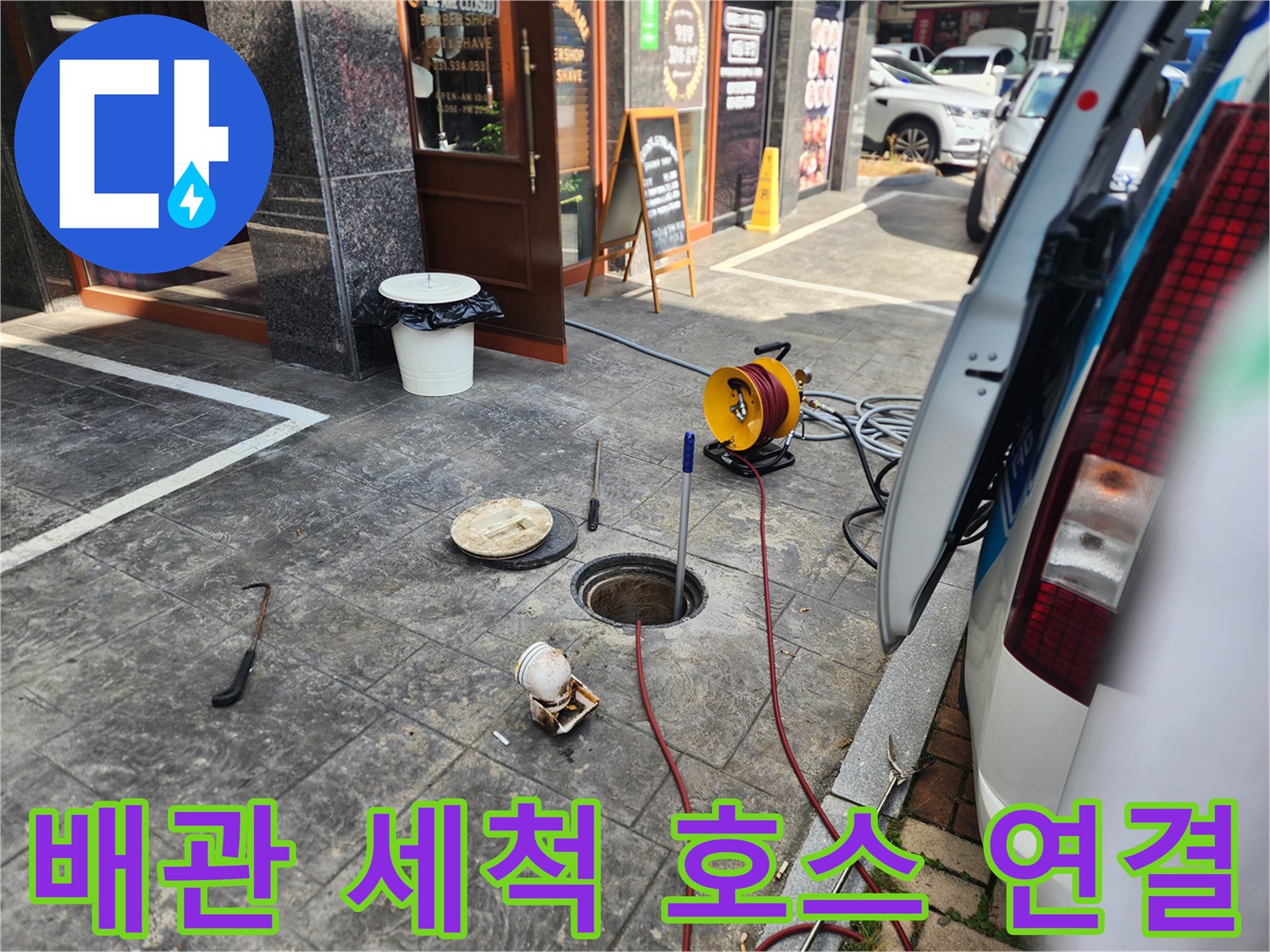 맨홀 입구와 연결된 고압 세척용 붉은색 호스 및 장비