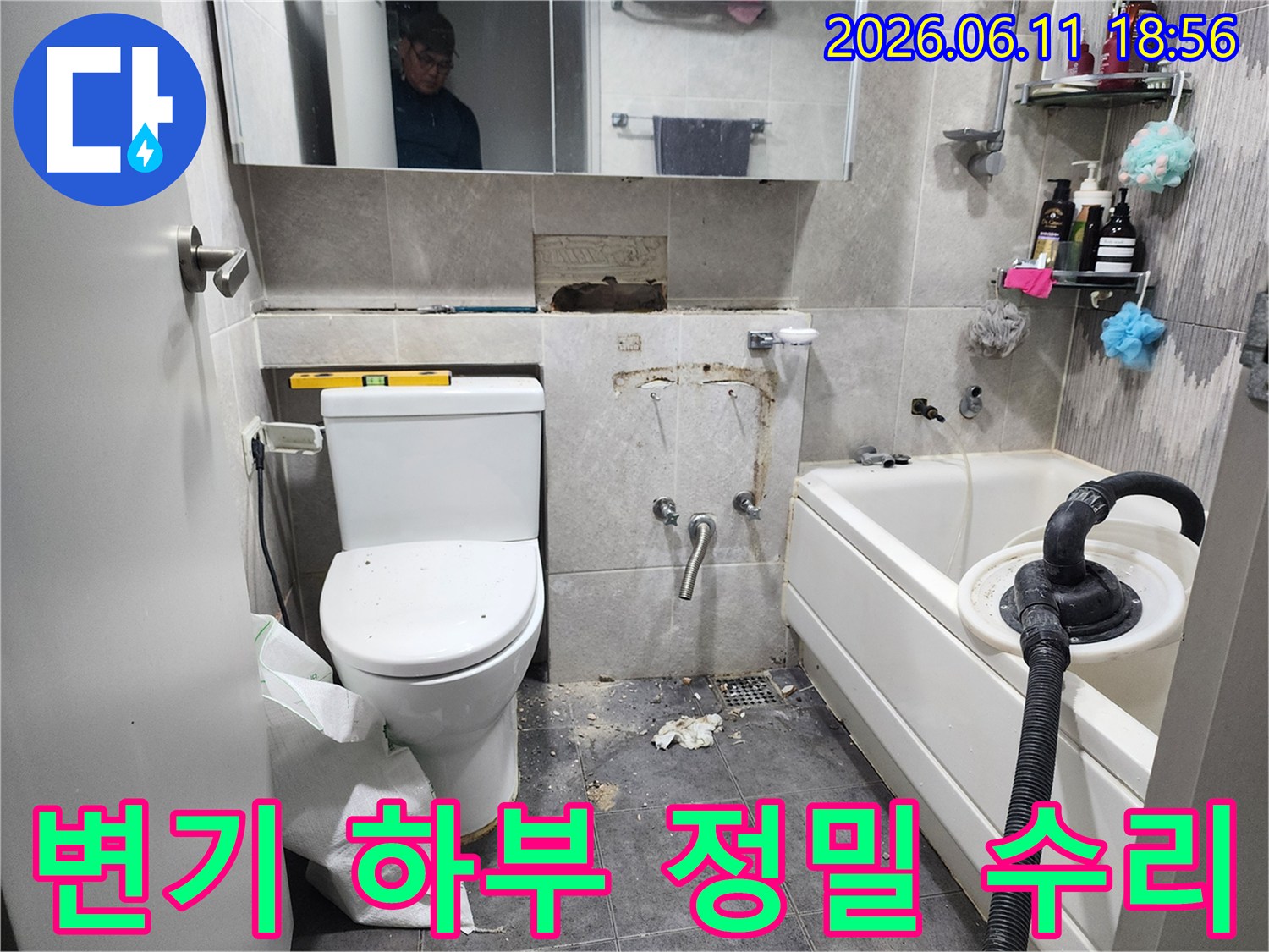 이 이미지는-동대문구 아파트 화장실에서-변기 하부에서 발생한 누수를 해결하기 위해-타일을 제거하고-배관 연결 부위를-정밀하게 수리하는-작업 현장을 보여줍니다