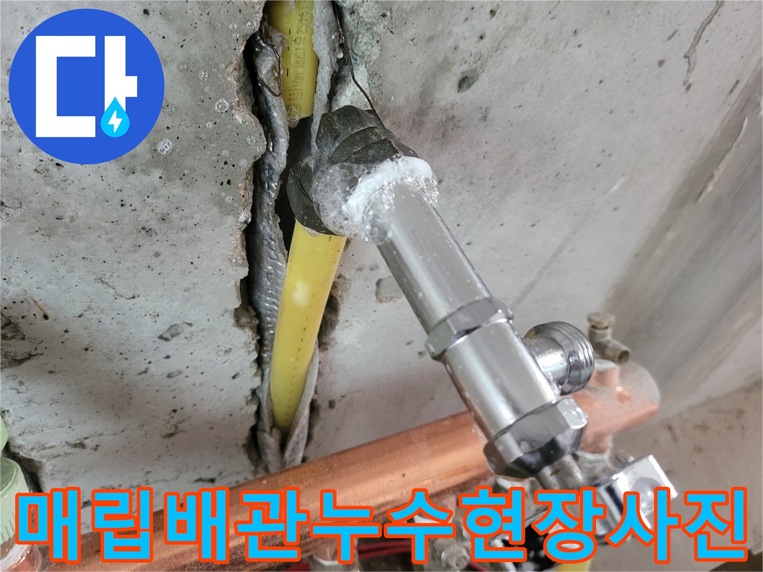 콘크리트 틈 사이로 노출된 노란색 배관과 분배기 부속의 모습입니다.