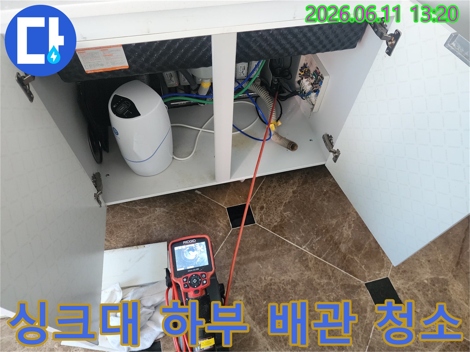 싱크대 아래쪽 배수 호스와 연결된 배관 부위의 오염을 확인하며 장비를 운용하는 모습입니다.