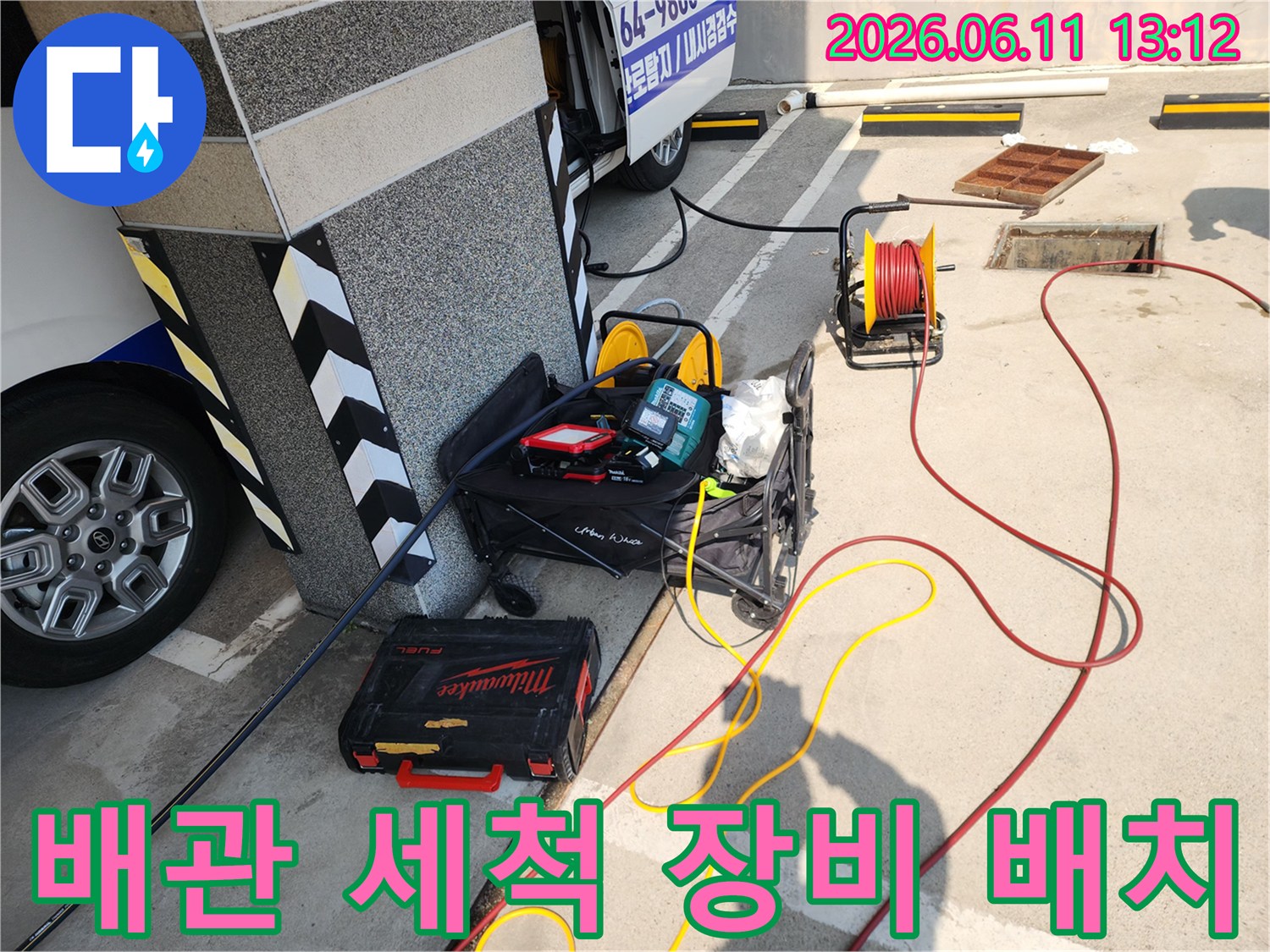 건물 외벽 옆에 놓인 고압 세척기 호스와 공구 박스