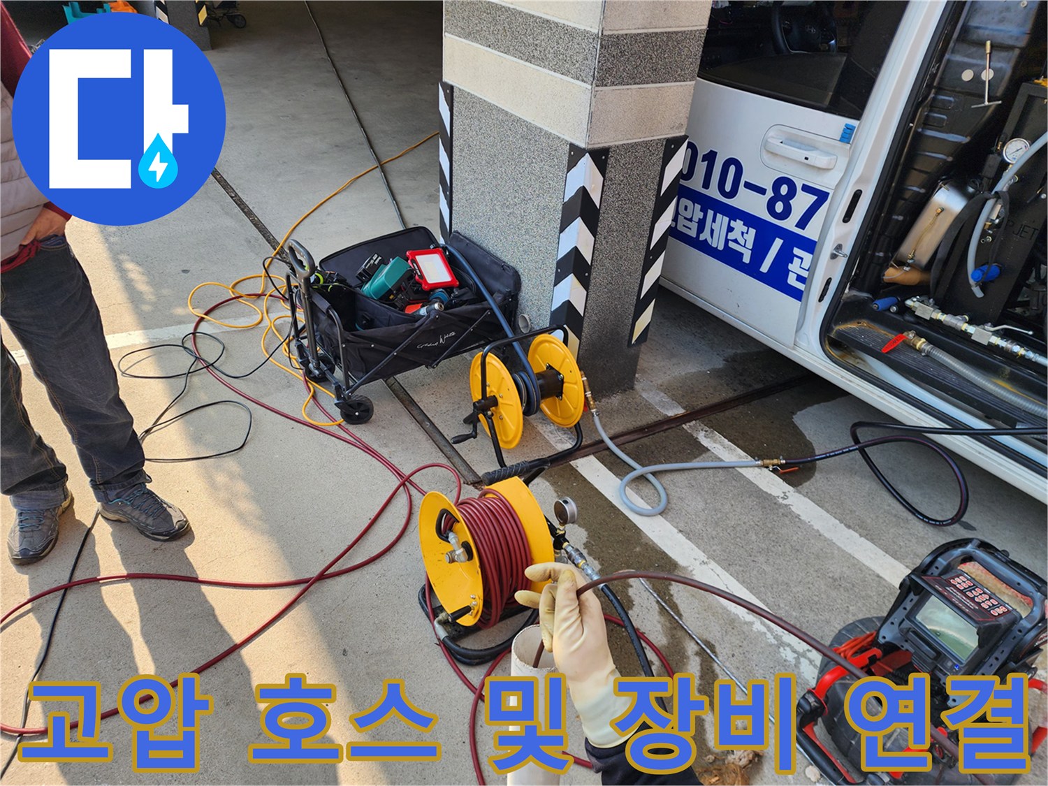 바닥에 배치된 고압 세척용 호스 릴과 배관 점검 장비의 모습입니다.