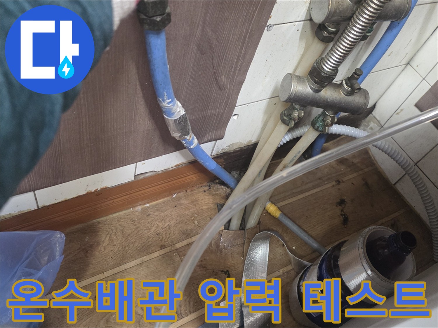 주방 하부장 내부의 파란색 배관과 연결된 수압 점검용 호스