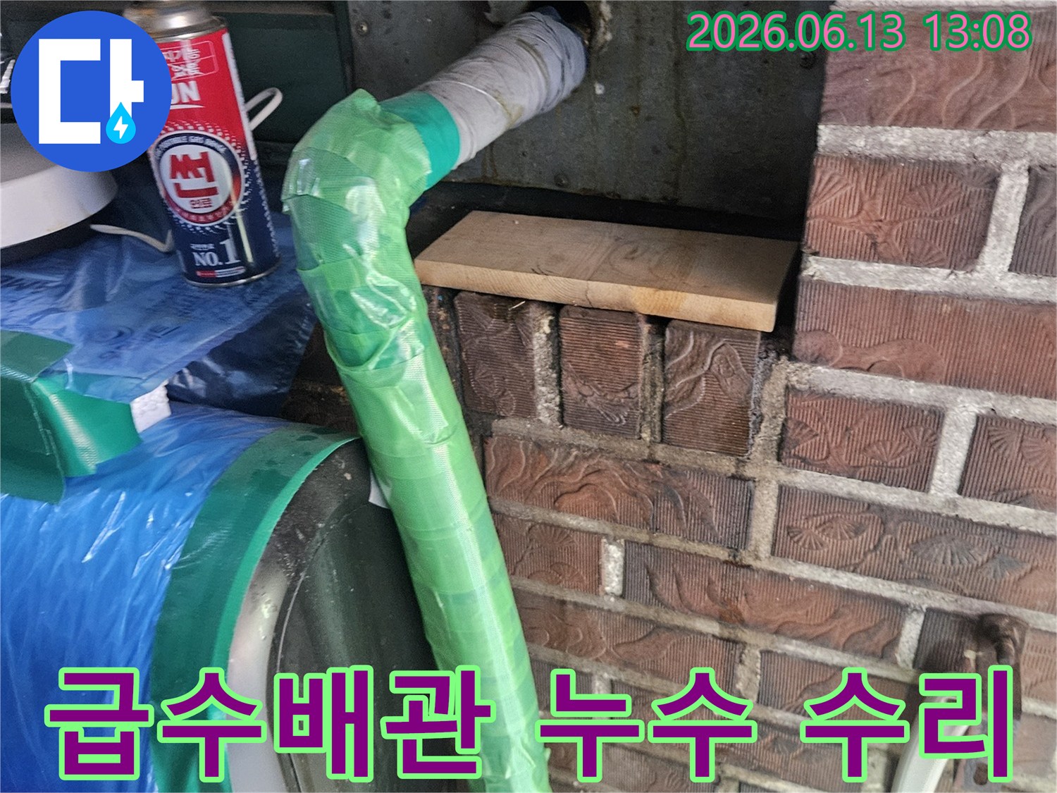 공장 건물 벽면에서 나온 급수 배관의 누수 지점을-특수 테이프로 감싸고 토치로 열처리하여 수리하는 모습