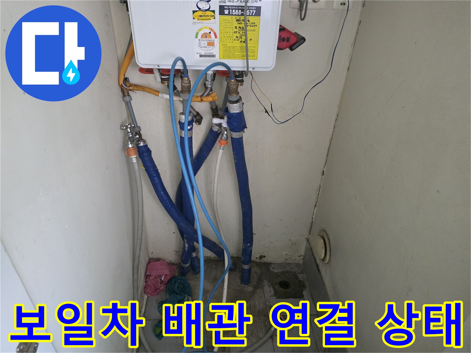파란색 급수 호스와 금속 밸브가 연결된 보일러 하부 모습