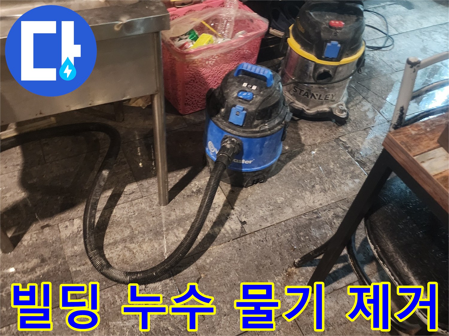 빌딩 누수 현장에서-바닥에 고인 물을-신속하게 흡입하고-습기를 제거하기 위해-사용되는-산업용 석션 장비 두 대가-바닥에 놓여있는 모습입니다.