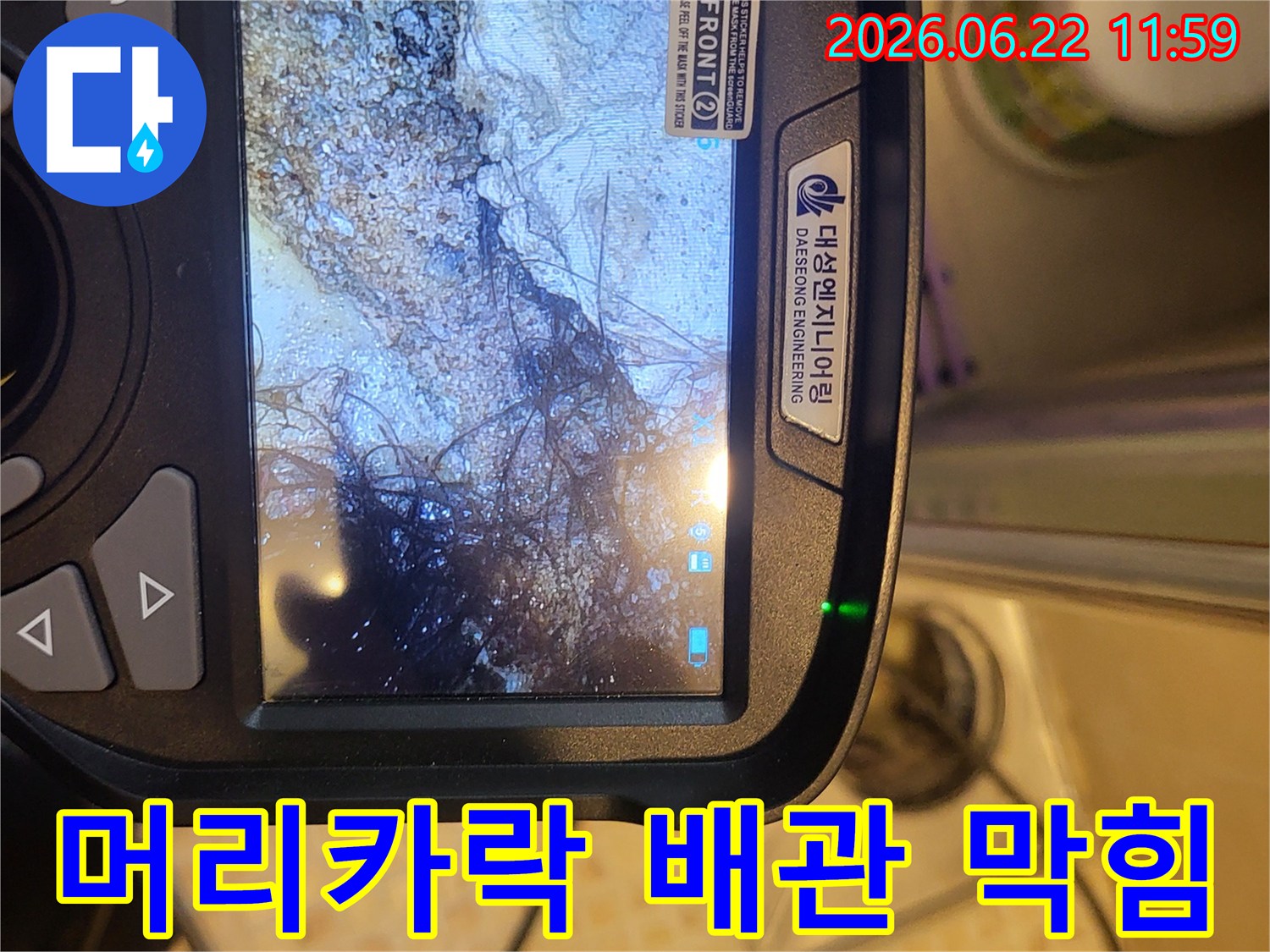 누수 탐지 전문가가-배관 내시경으로 오수관 내부를 촬영하여-머리카락과 슬러지로 막힌 상태를 확인하는 모습