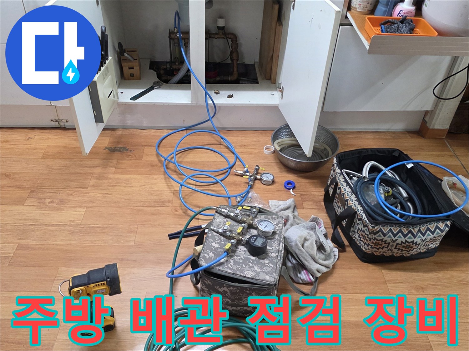 싱크대 하부장 근처에 놓인 배관 압력 검사용 가스 탐지 장비와 호스