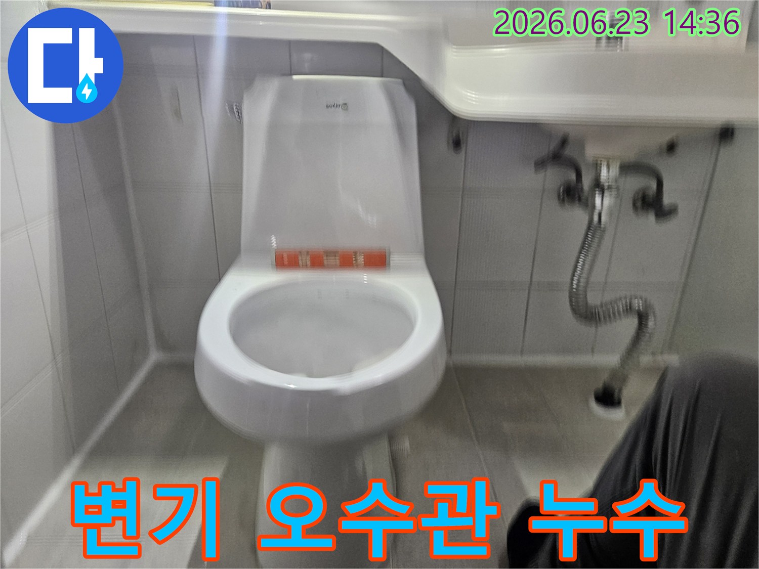 이 사진은 욕실 변기 오수관 연결 부위에서 발생할 수 있는 누수를-전문가가 점검하는 모습을 보여줍니다.
