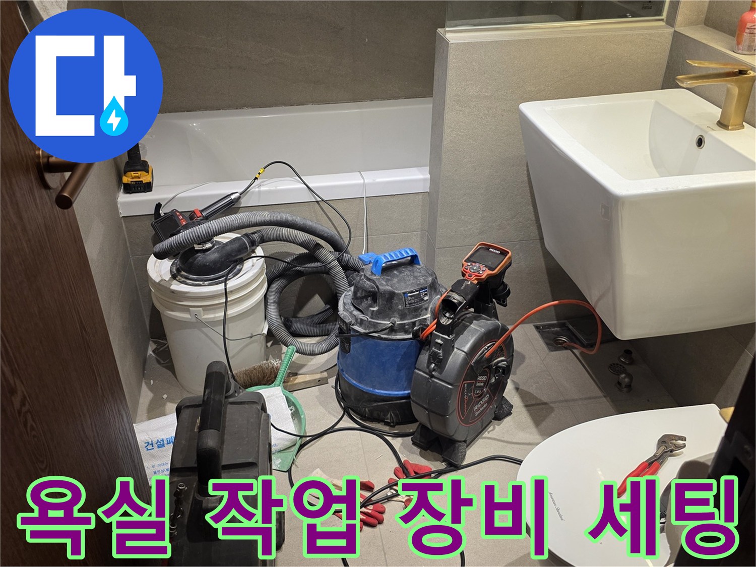 욕실 바닥에 배치된 배관 청소용 습식 진공청소기와 각종 수공구들