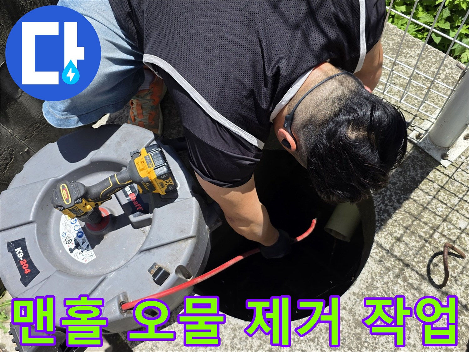 오수 맨홀 입구에서 흡입 호스를 사용하여 청소하는 모습