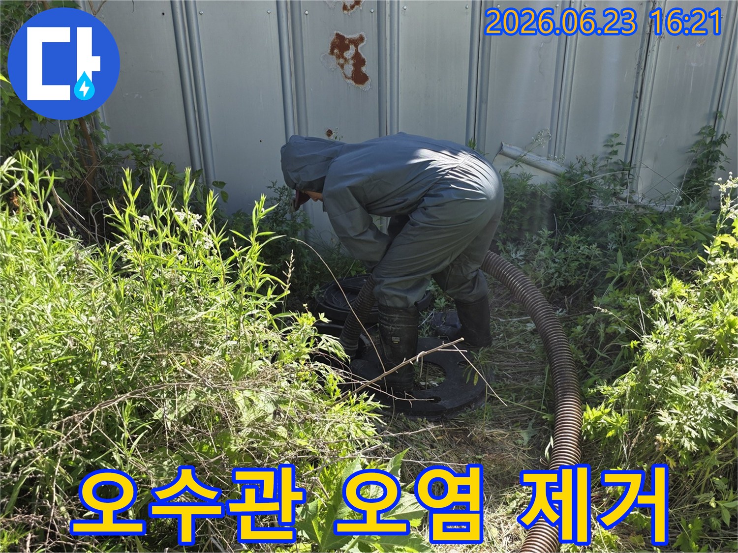 전문 작업자가 보호복을 입고 오수관 주변의 오염 물질을 제거하기 위해 흡입 작업을 하는 모습