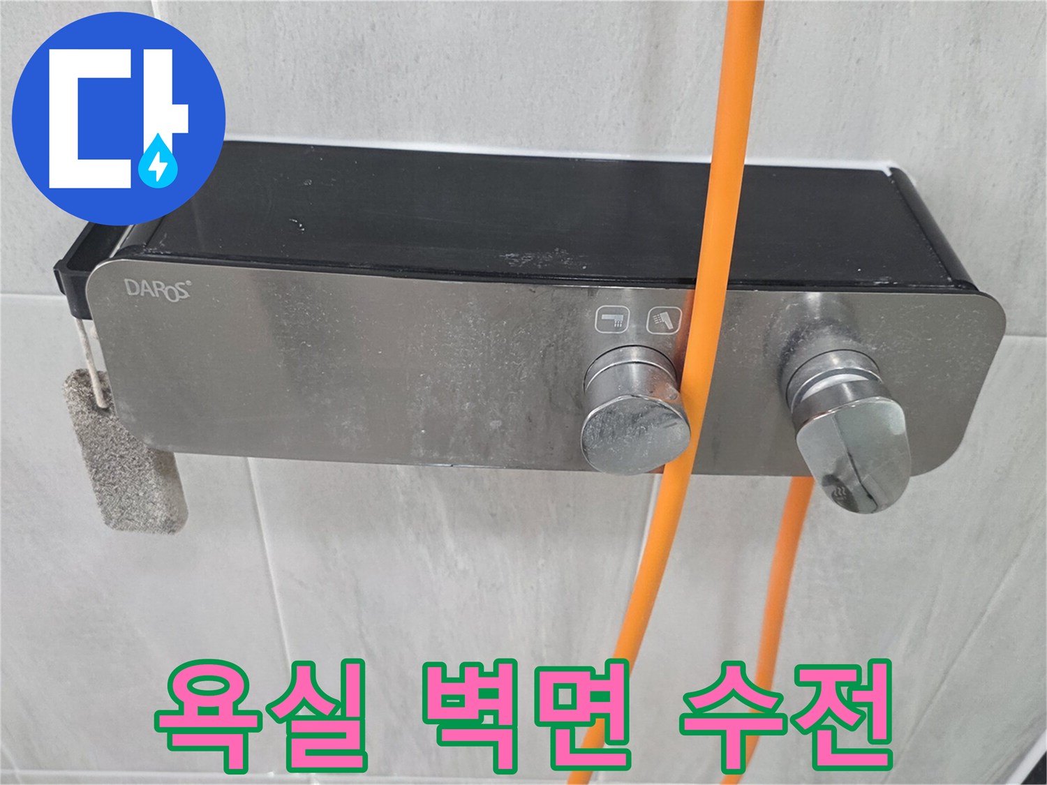벽면에 설치된 금속 수전과 주황색 호스 연결 부위