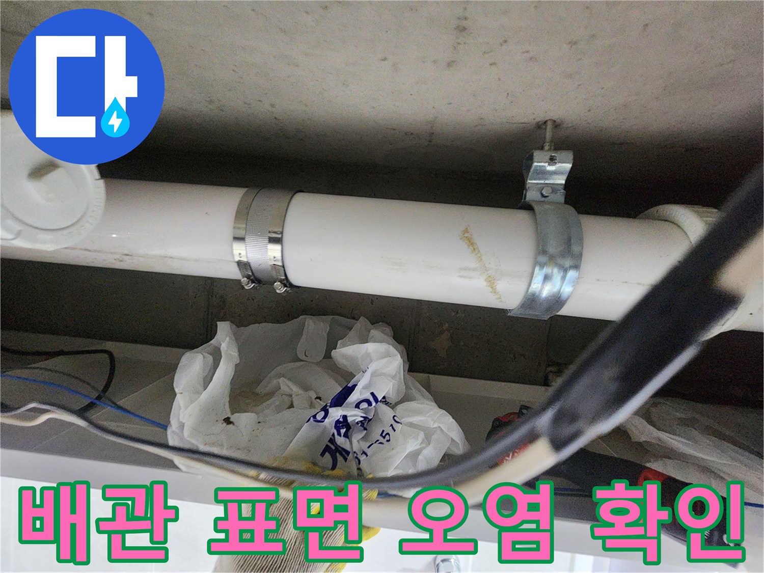 흰색 배관과 금속 클램프가 결합된 천장 내부 모습