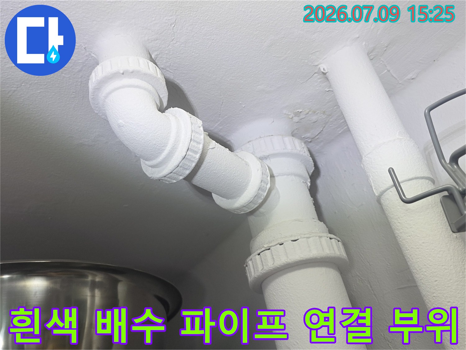 하얀색으로 도색된 세탁실 배수용 PVC 파이프와 엘보우 연결부 상세 사진