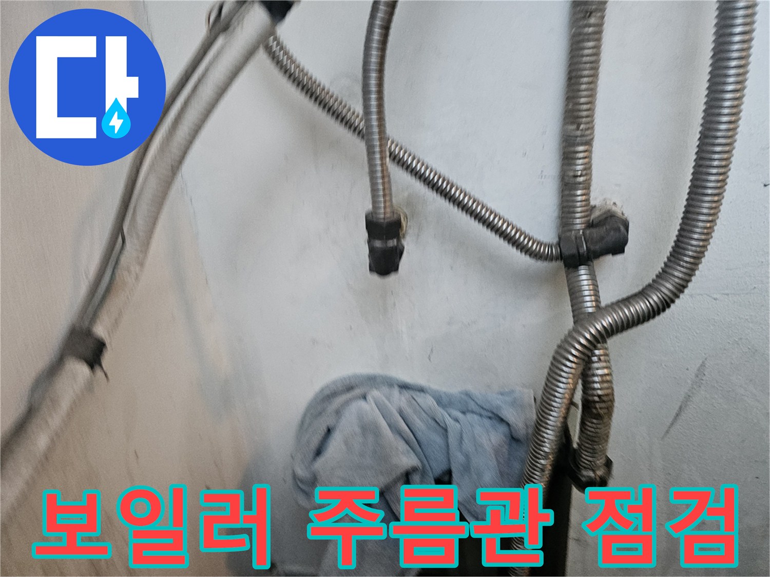 보일러 하단에 연결된 은색 주름관과 배관 연결 부위 모습입니다.