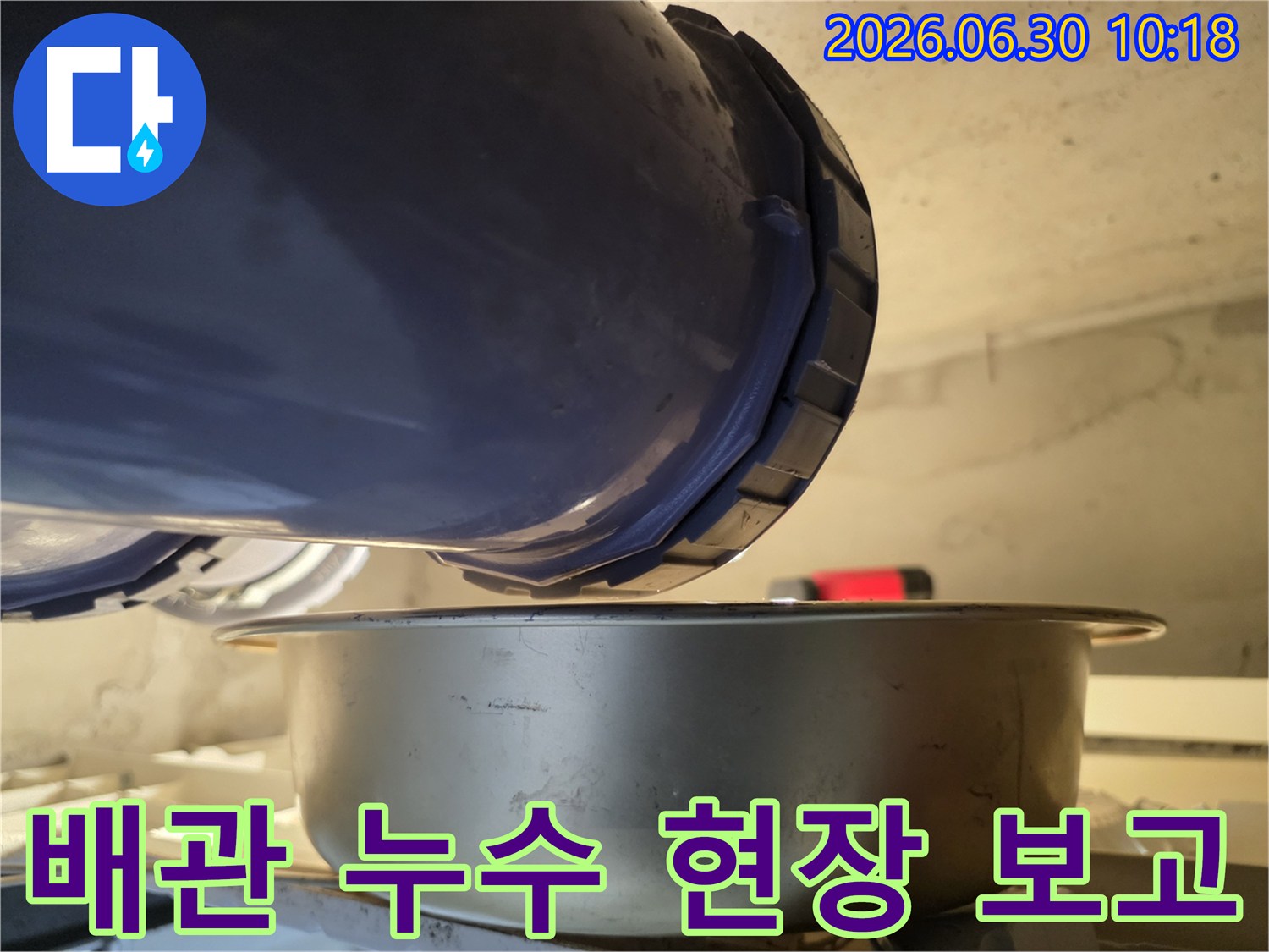 누수-현장에서-배관의-연결-부위에서-물이-새는-것을-발견하고-아래에-물받이를-놓아-누수-상황을-보고하고-있는-모습입니다.