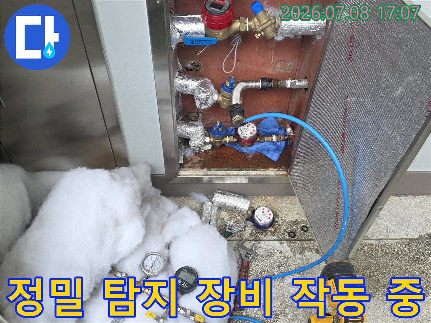 화장실 배관에 연결된 파란색 호스와 전문 기기를 활용해 정밀 진단하는 장면
