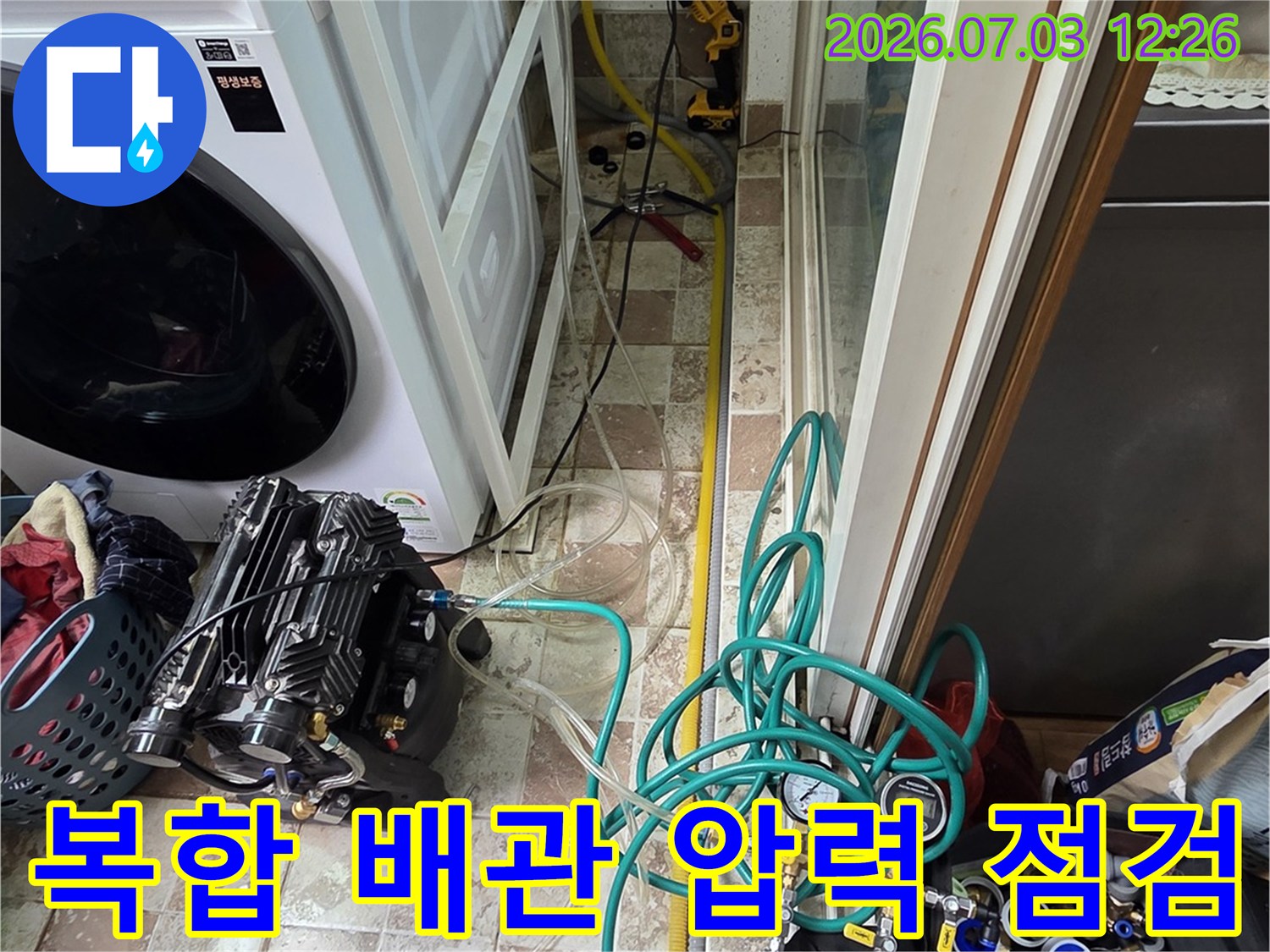세탁기 옆 복잡하게 얽힌 배관에 호스를 연결하여 누수 여부를 정밀 테스트하는 모습