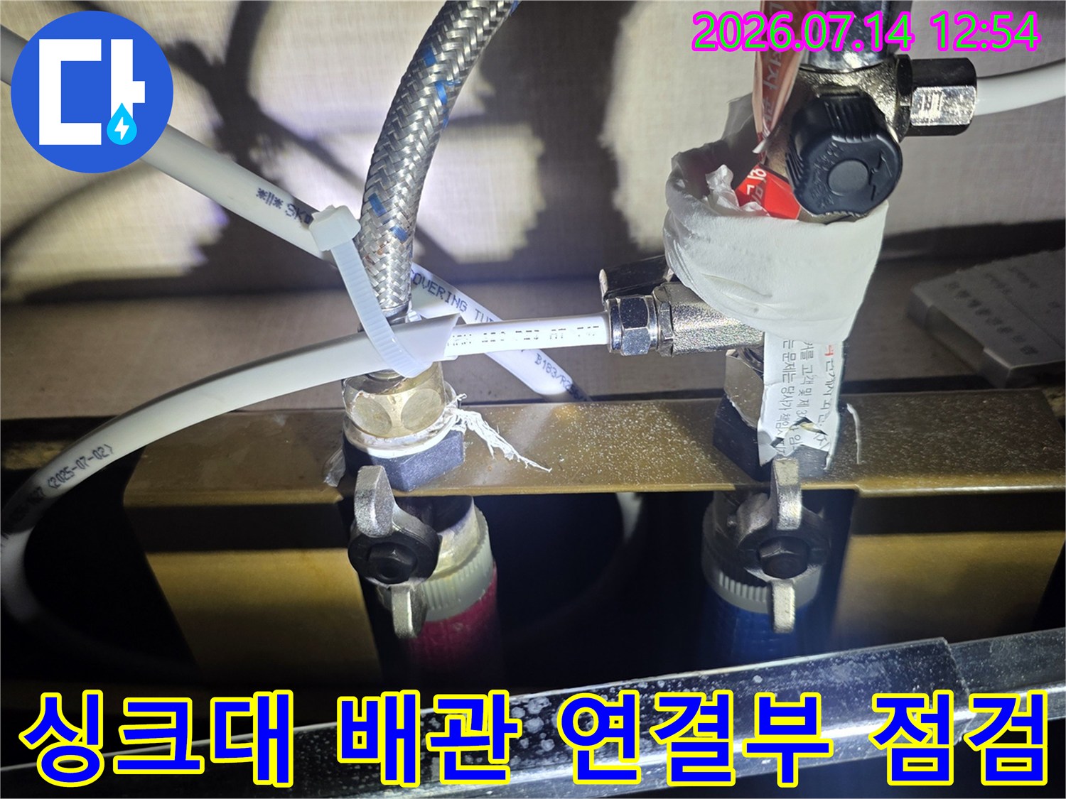 싱크대 아래 노출된 수도 배관과 압력 게이지가 설치된 정밀 점검 장면