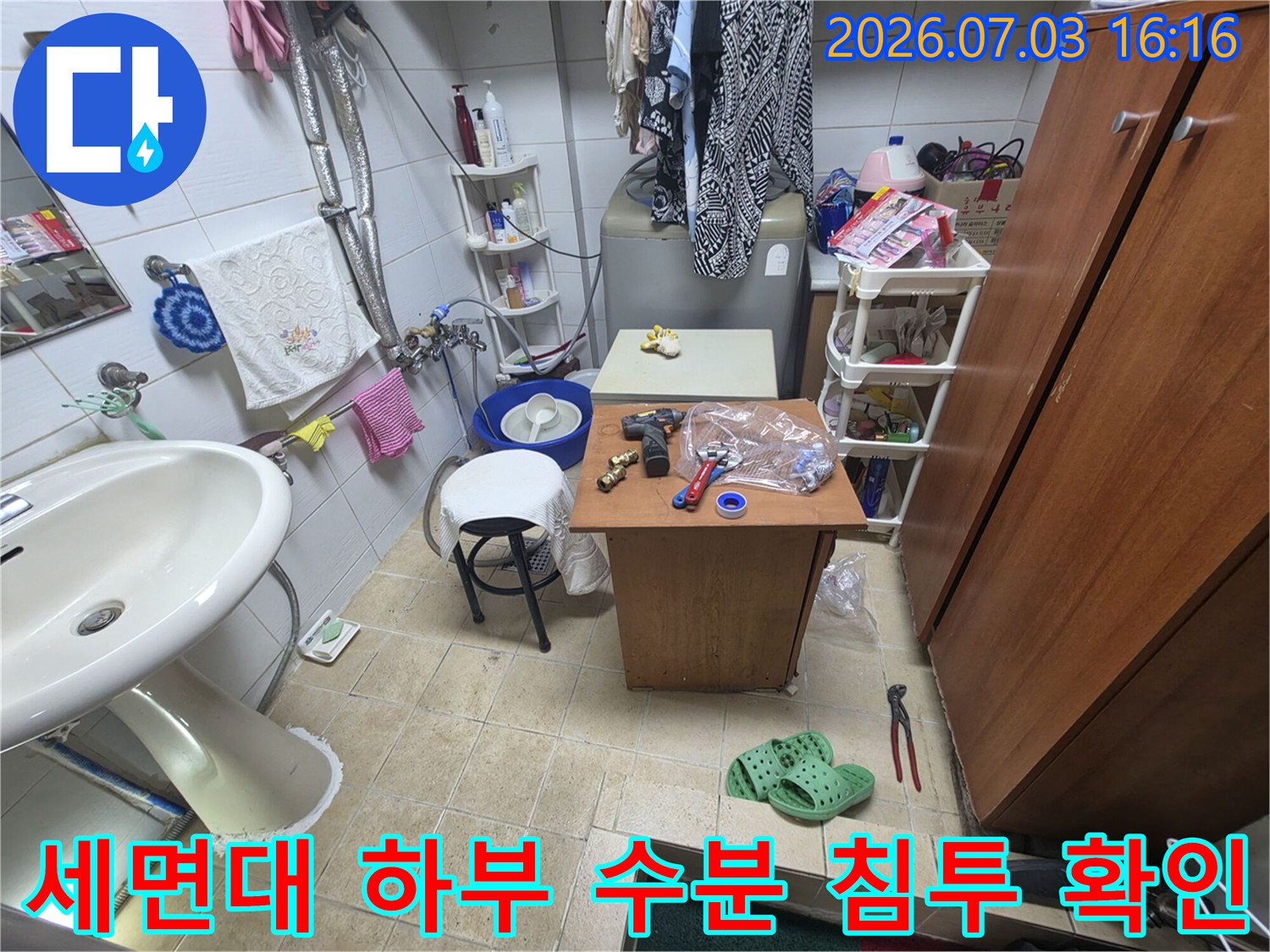세면대 밑에 노출된 배관 연결 부위의 상태를 정밀히 조사하는 모습