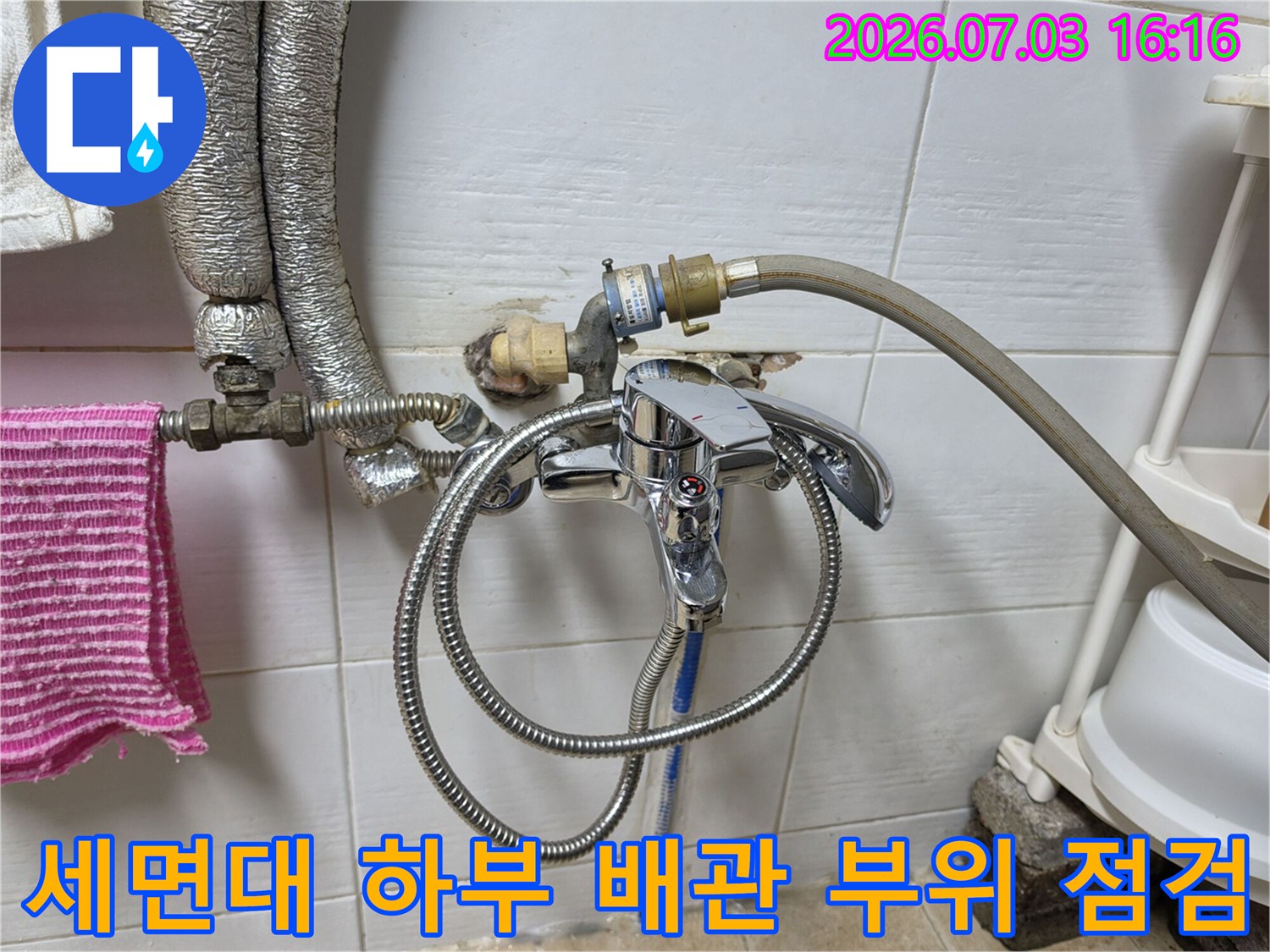세면대 아래 노출된 수도 배관과 호스 연결 상태