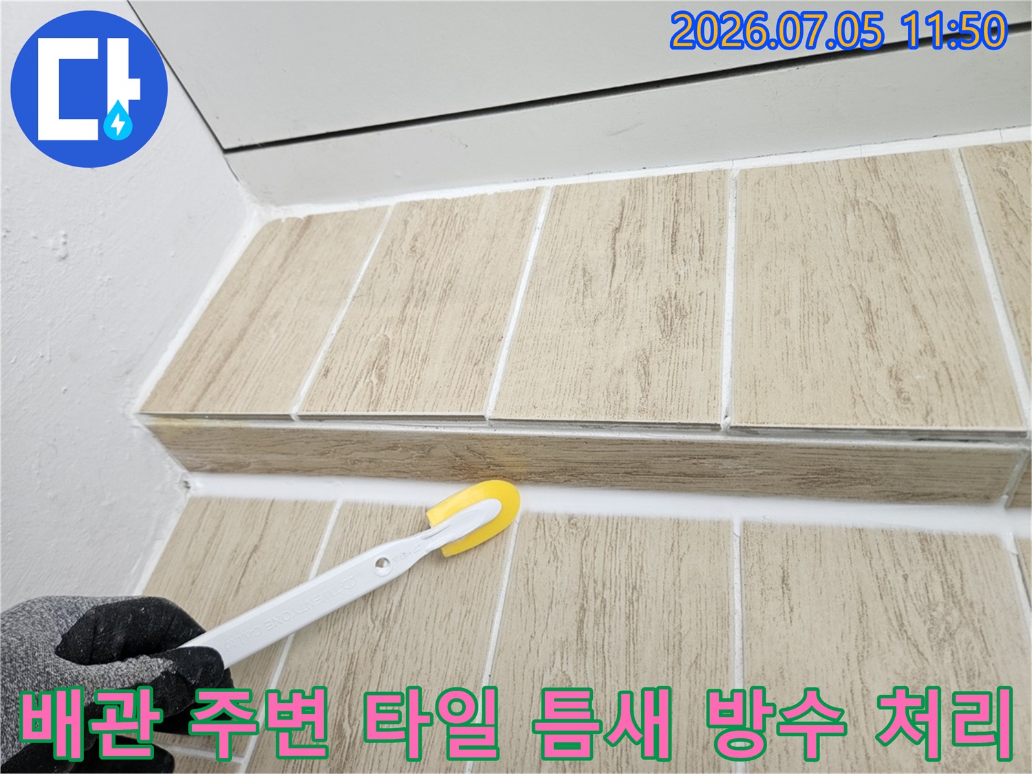 베란다 우수관 옆 타일 줄눈에 흰색 실란트를 채우는 작업 모습