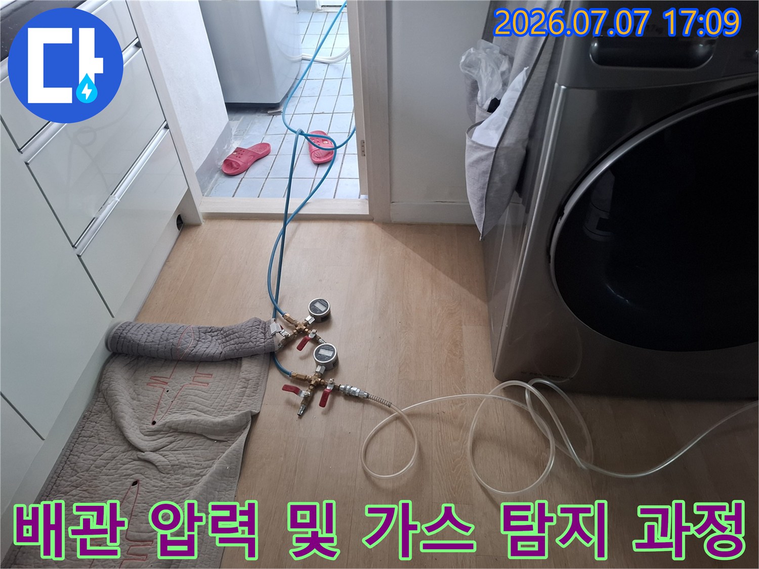 가스 분석 장비와 호스를 연결하여 다용도실 내 배관의 이상 유무를 점검하는 모습