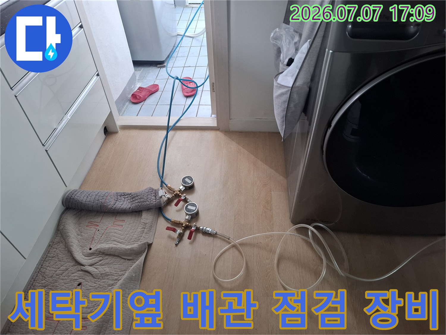 세탁기 옆에 연결된 배관과 압력 점검을 위한 게이지가 설치된 현장 모습