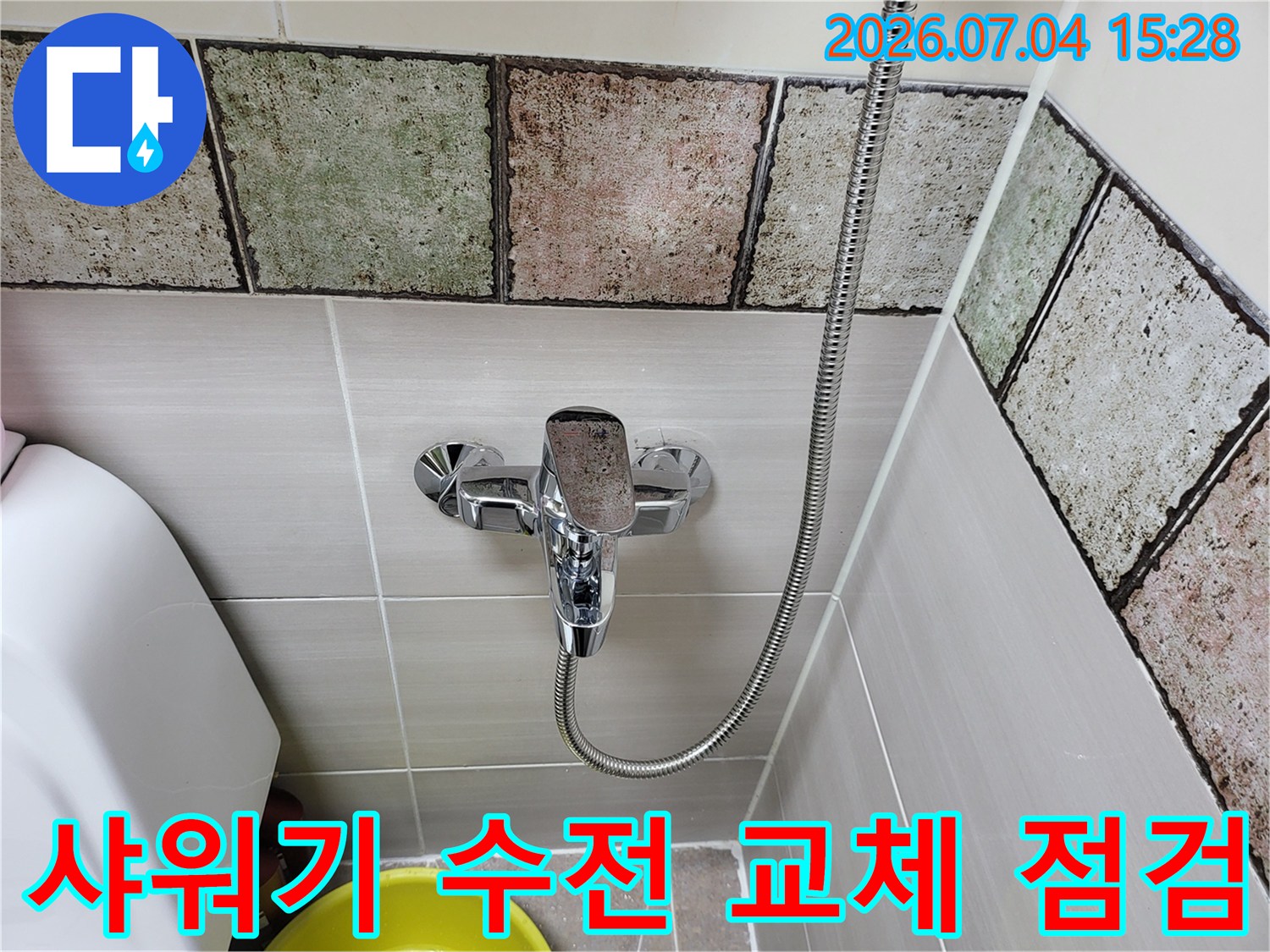 타일 벽면과 설치된 샤워기 수전 및 배관의 모습